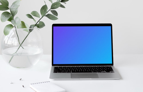 MacBook mockup on a white table with a bowl-shaped flower vase at the side