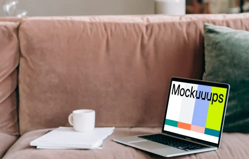 MacBook Pro mockup on a red sofa beside a couple of notepads