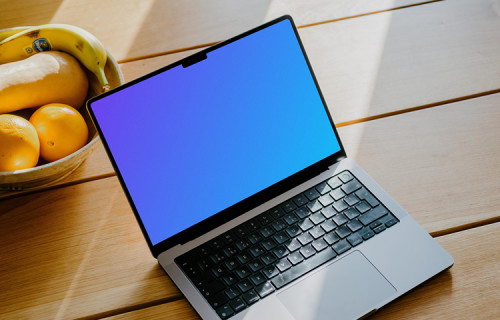MacBook Pro mockup on a table in front of a basket of fruits
