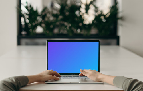 MacBook Pro mockup on a white table opposite an large mirror
