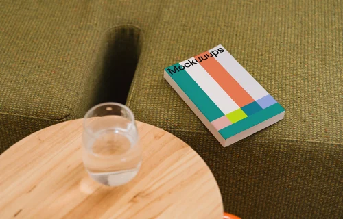 Paperback book mockup on a cozy green sofa