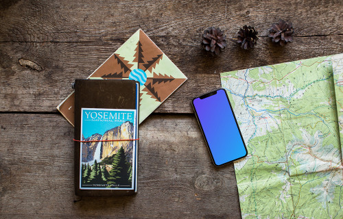 Rotated iPhone XS mockup with journal on the side
