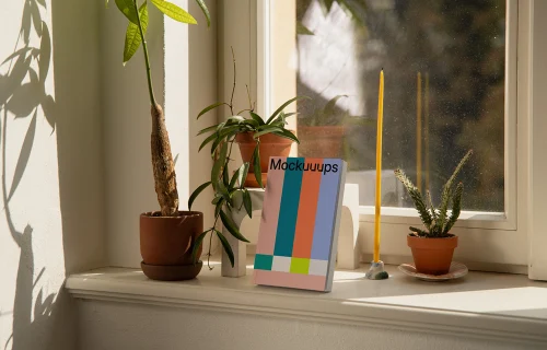 Softcover book mockup on a windowsill with plants