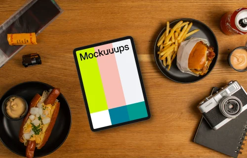 Tablet mockup between plates with hot-dogs