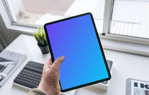 Tablet mockup held by man over work desk