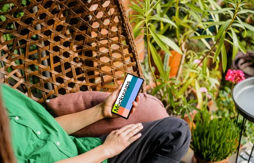 Woman holding a phone mockup surrounded by plants