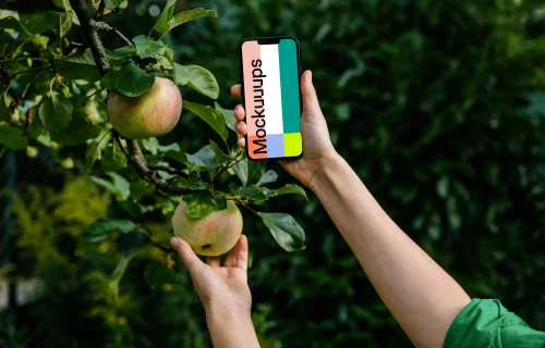 Woman holding an iPhone mockup while grabbing an apple