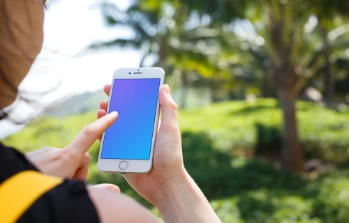 Woman holding iPhone 7 mockup in front of the palm tree