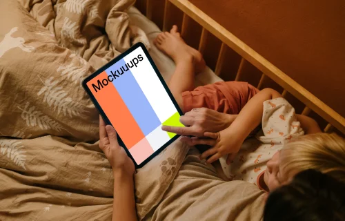 Woman with a child typing on an iPad mockup in bed