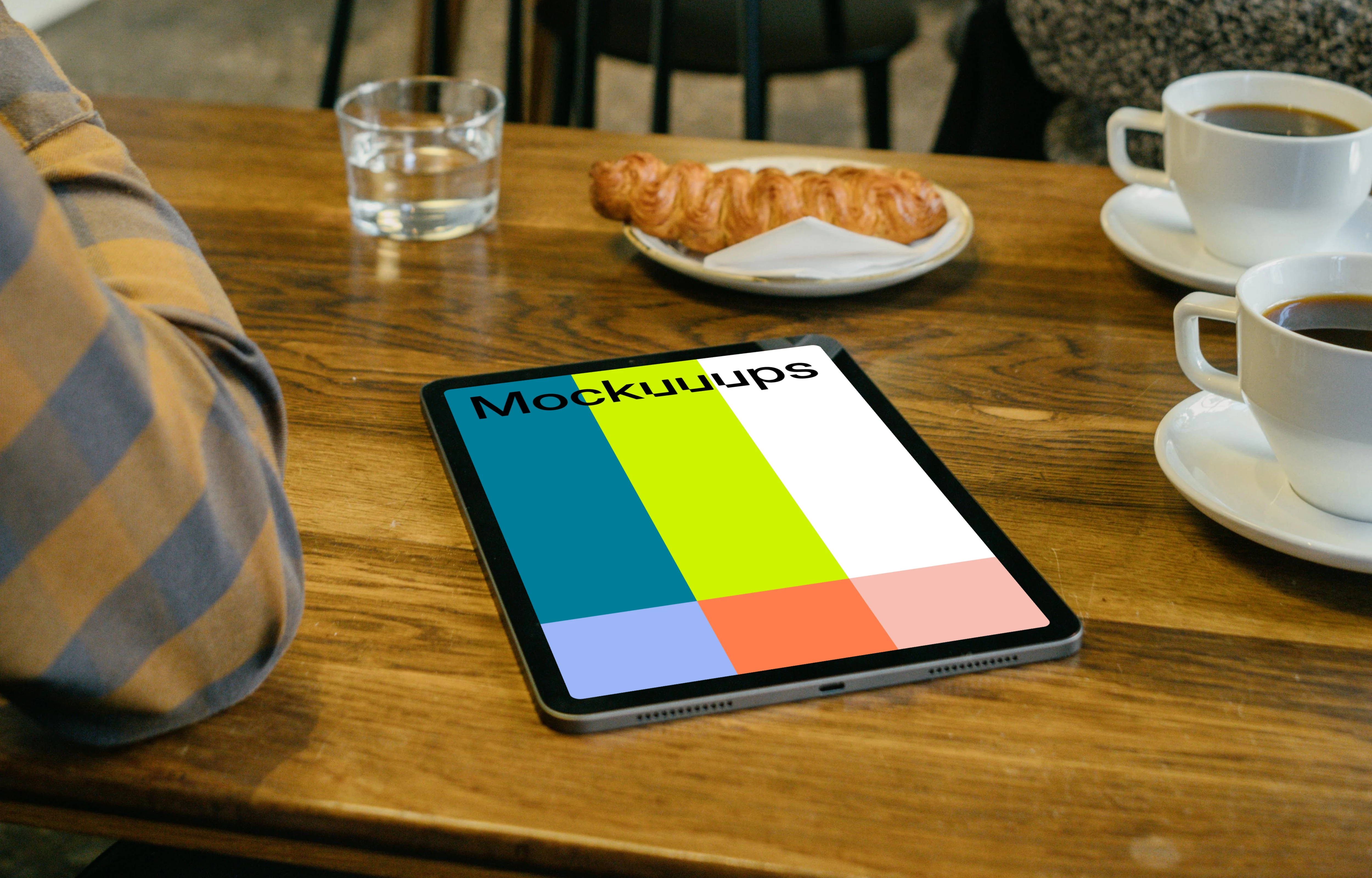 iPad mockup in front of a user beside a croissant