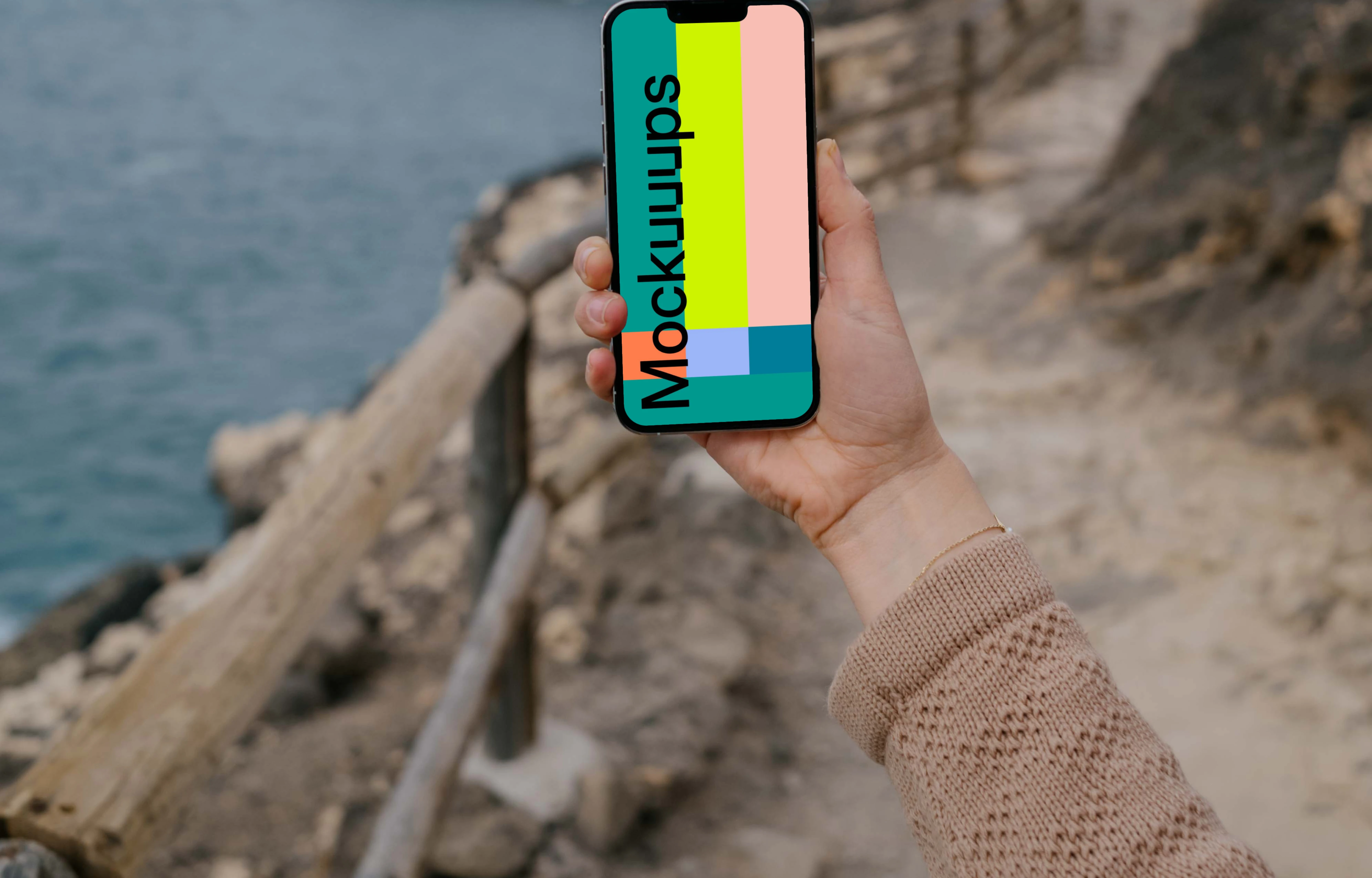 iPhone 13 Pro mockup held up beside the ocean