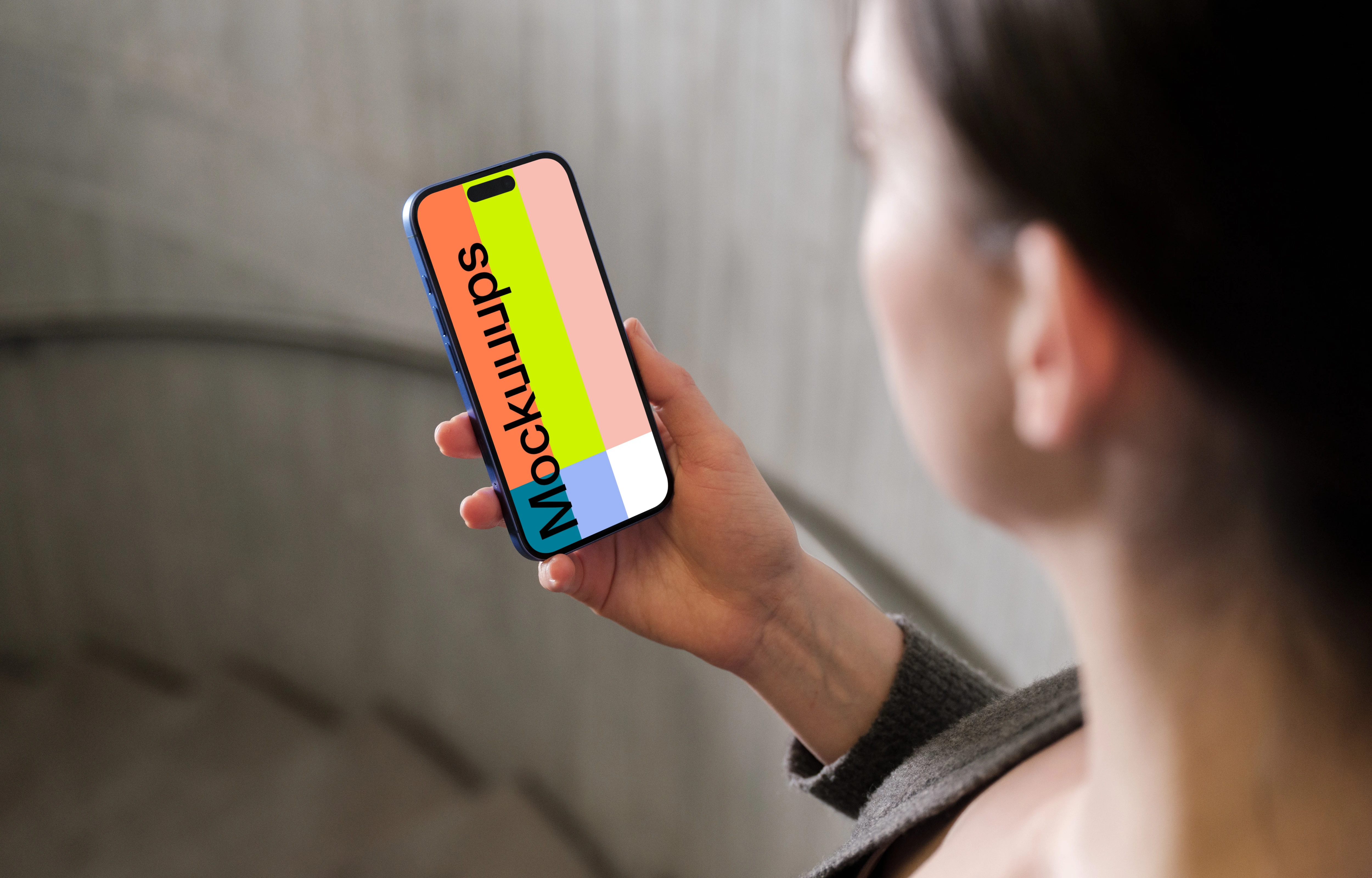 iPhone 16 mockup held in a woman's hand against concrete background