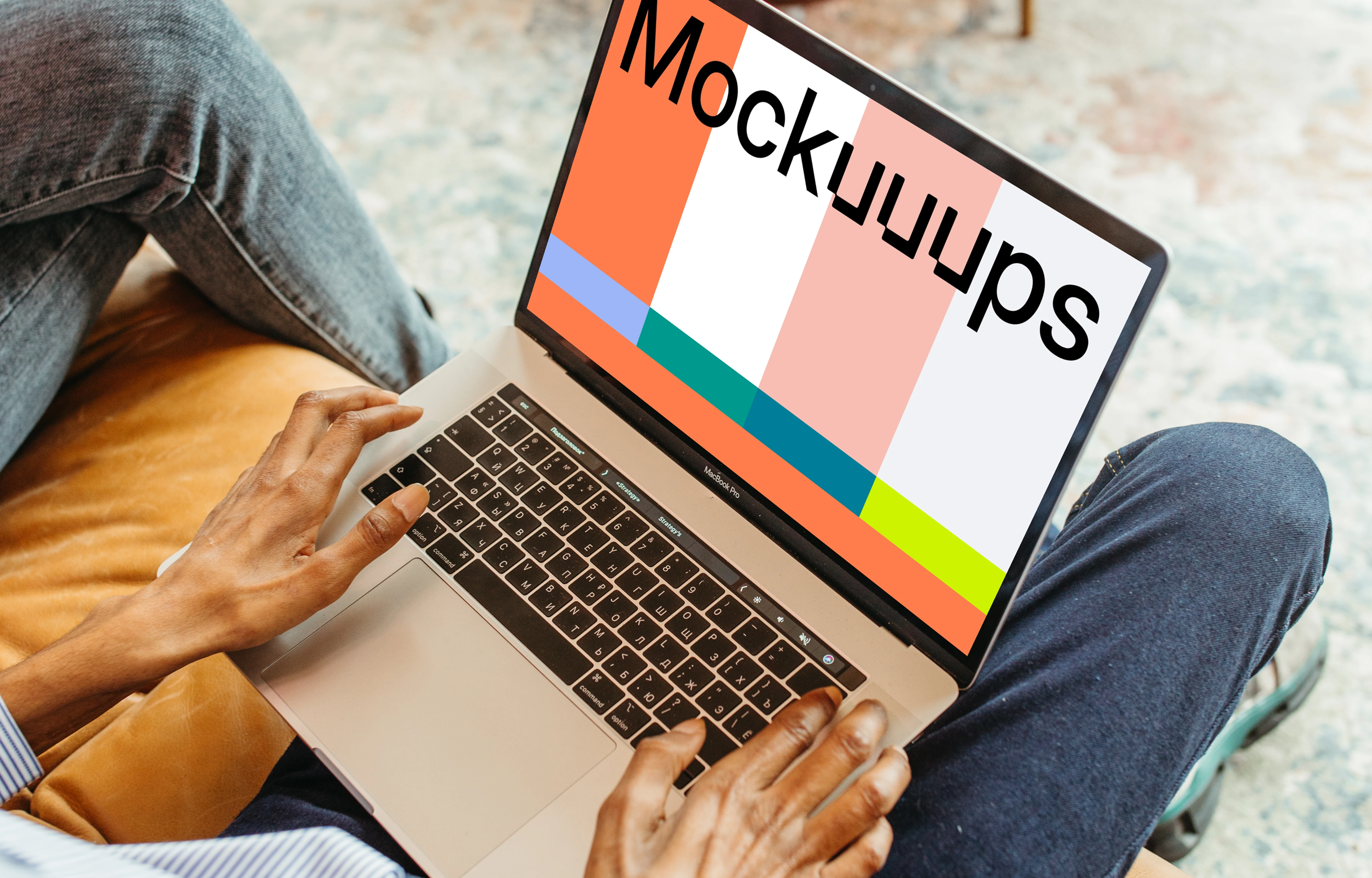 Male user sitting on a chair and using a MacBook Pro mockup