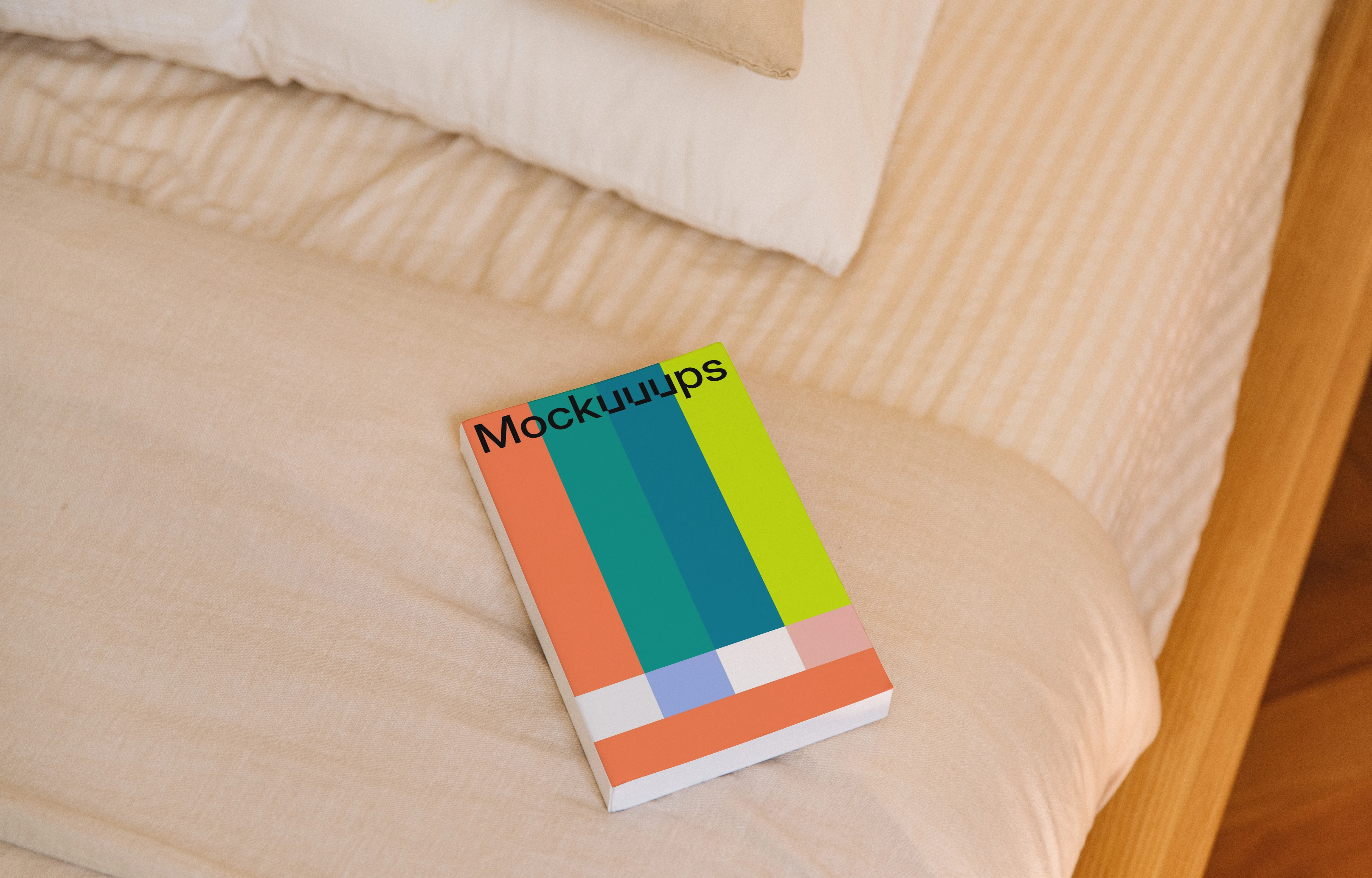 Softcover book mockup on a bed with light bedding
