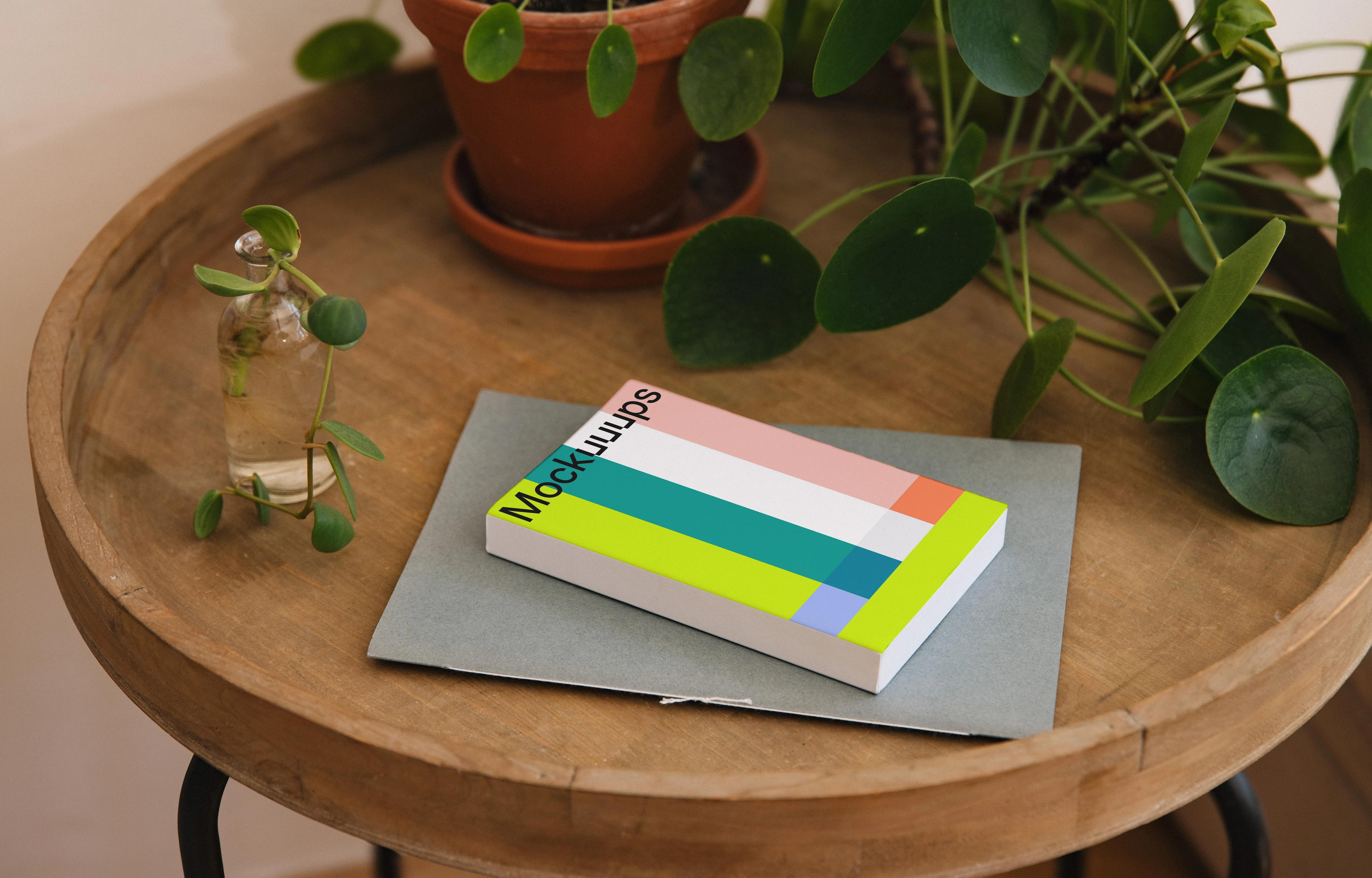 Softcover book mockup on a wooden table with plants