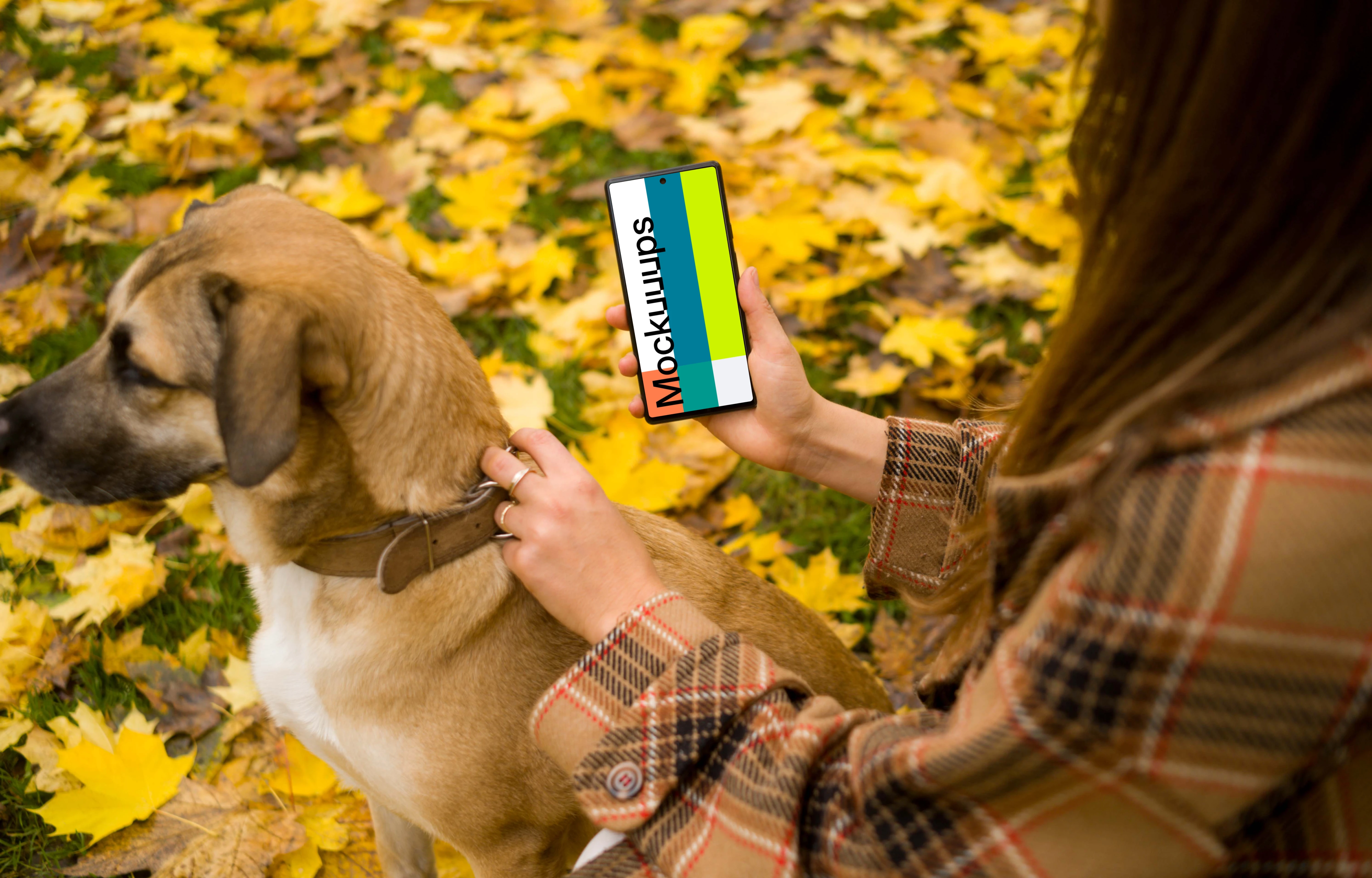 Woman holding a phone and dog in autumn themed park mockup