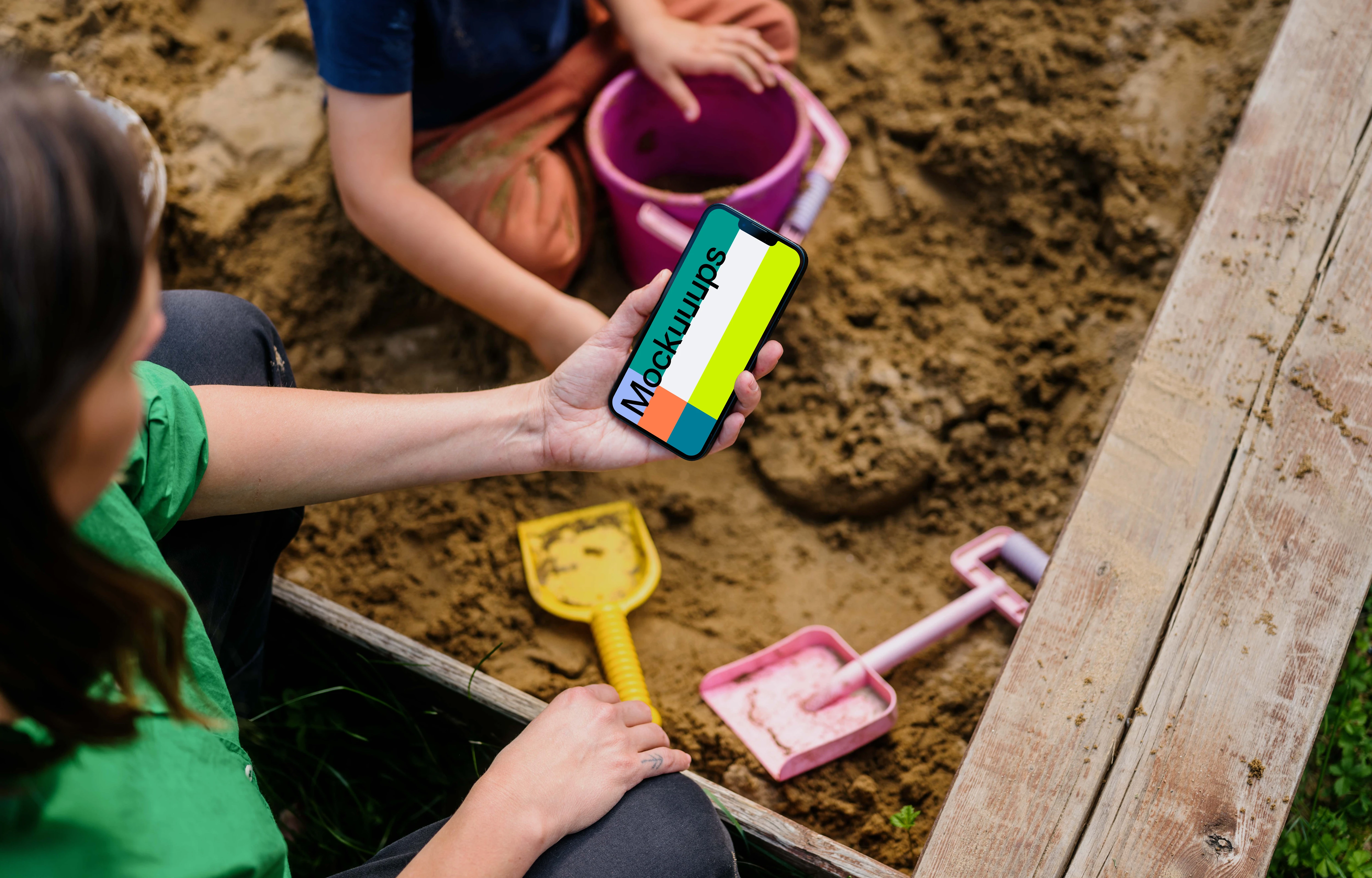 Woman holding an iPhone 13 mockup in sandpit