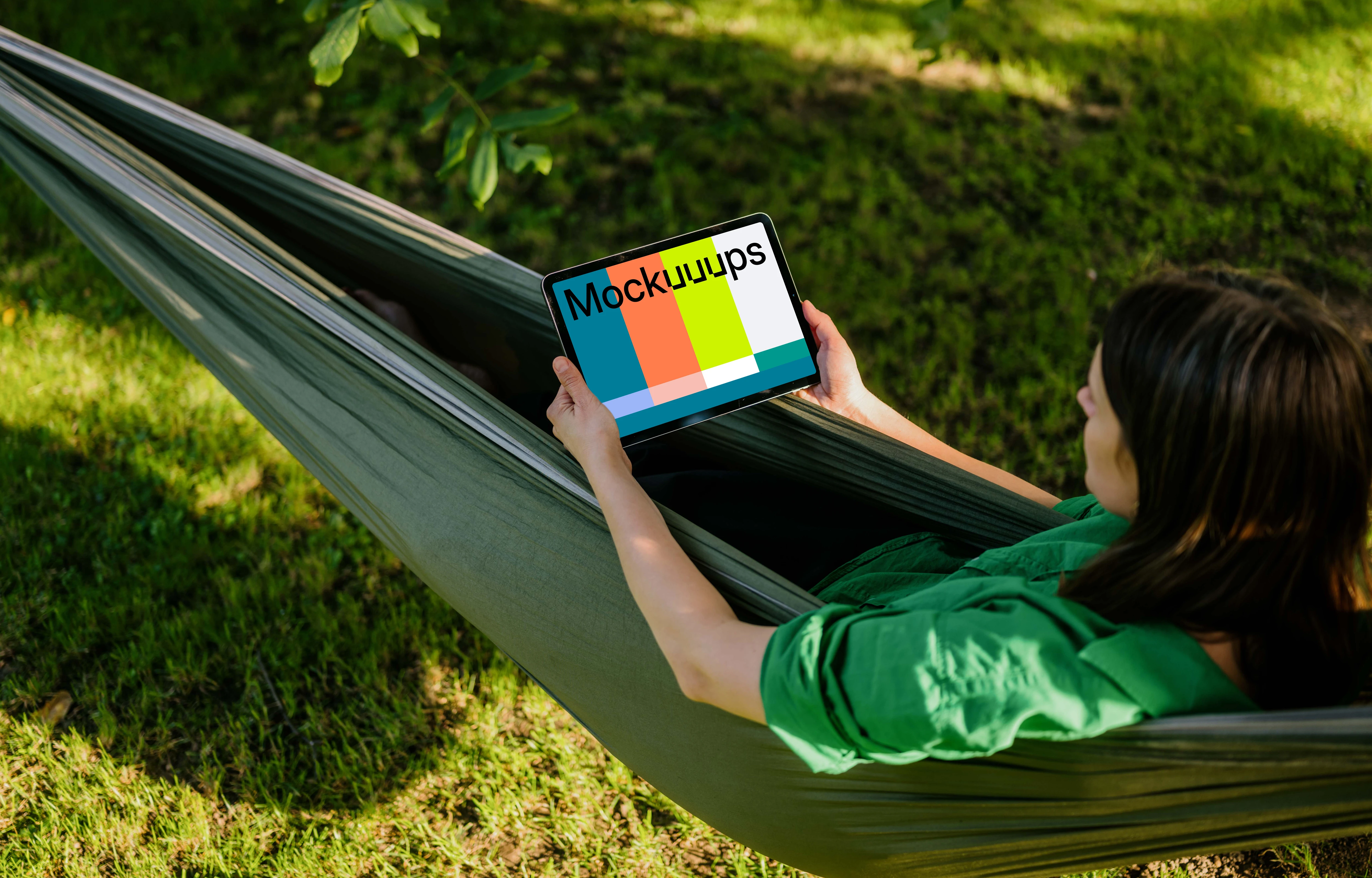 Woman laying in hammock while holding a tablet