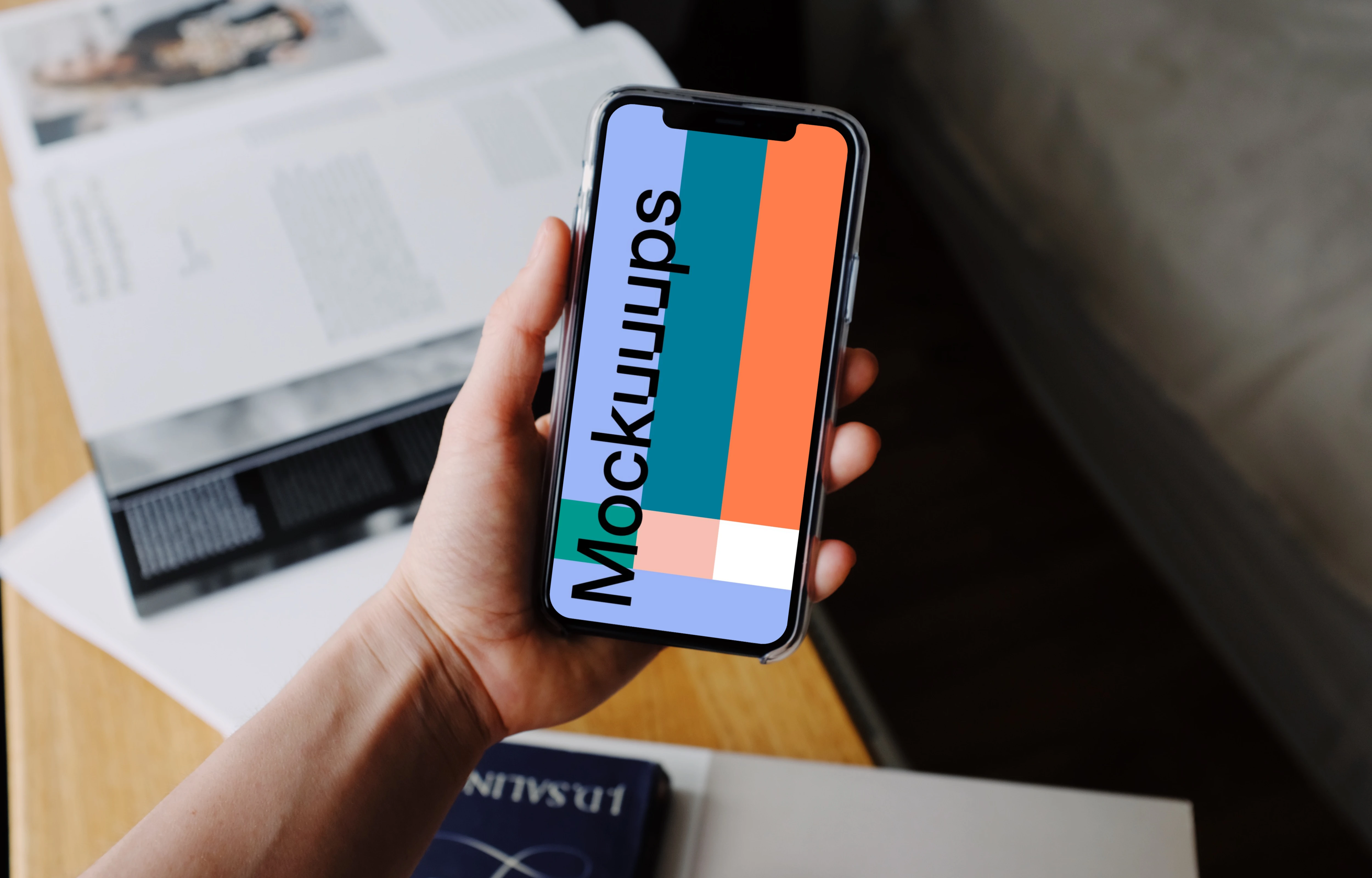 iPhone 12 Pro mockup held by user over textbooks