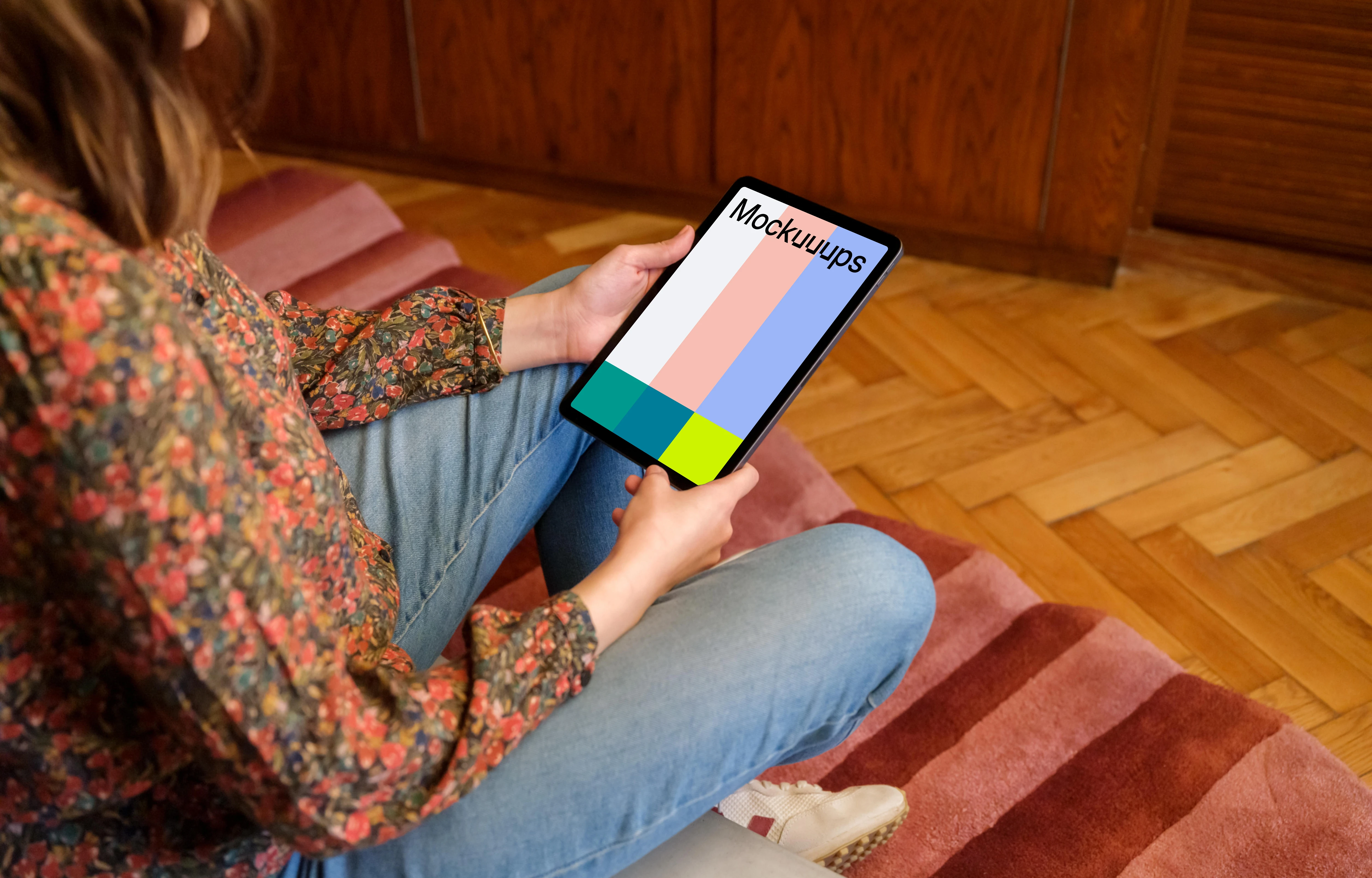 Female holding iPad mockup against a wooden background in the lounge