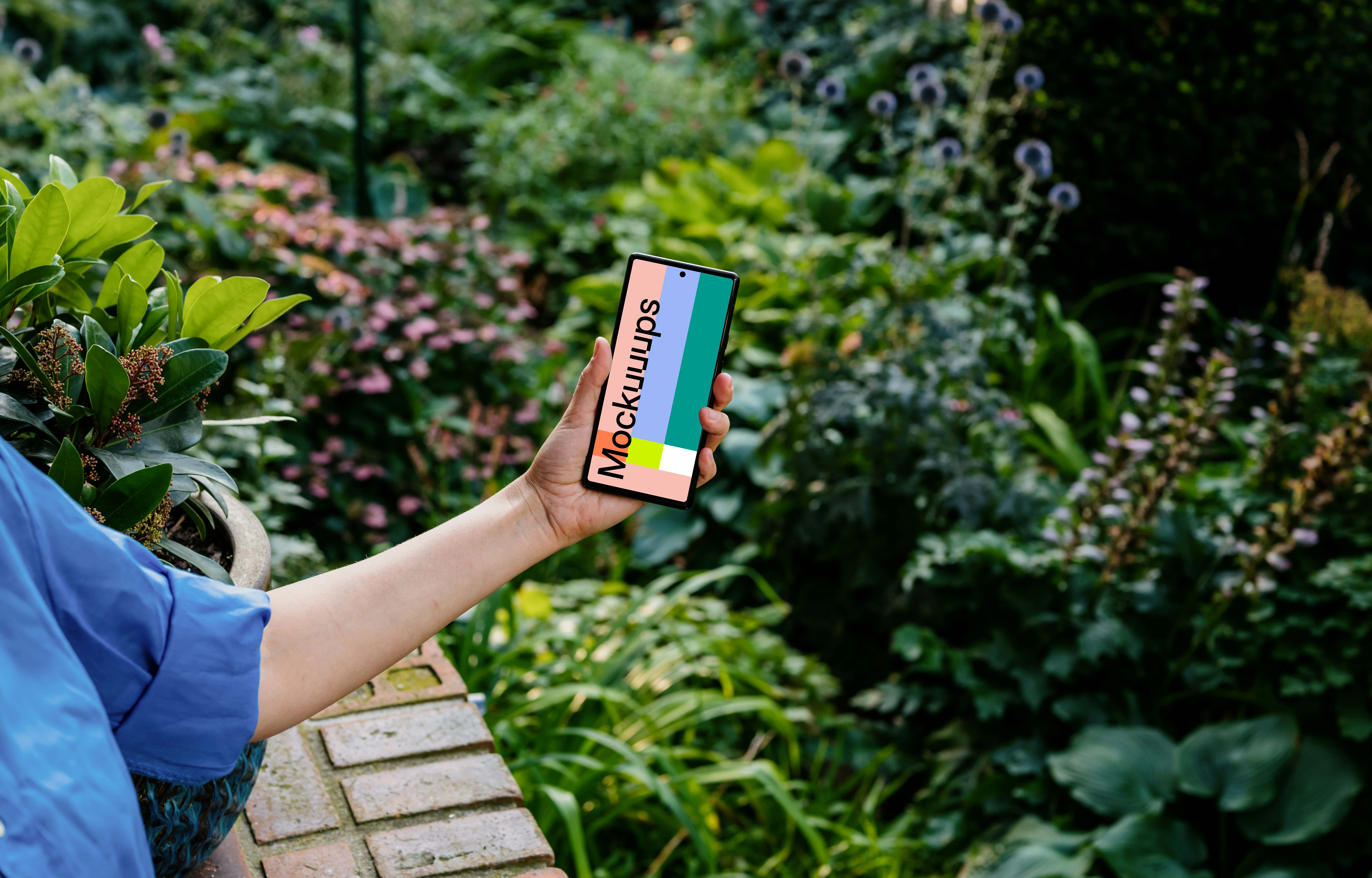 Hand holding a phone mockup with background full of plants