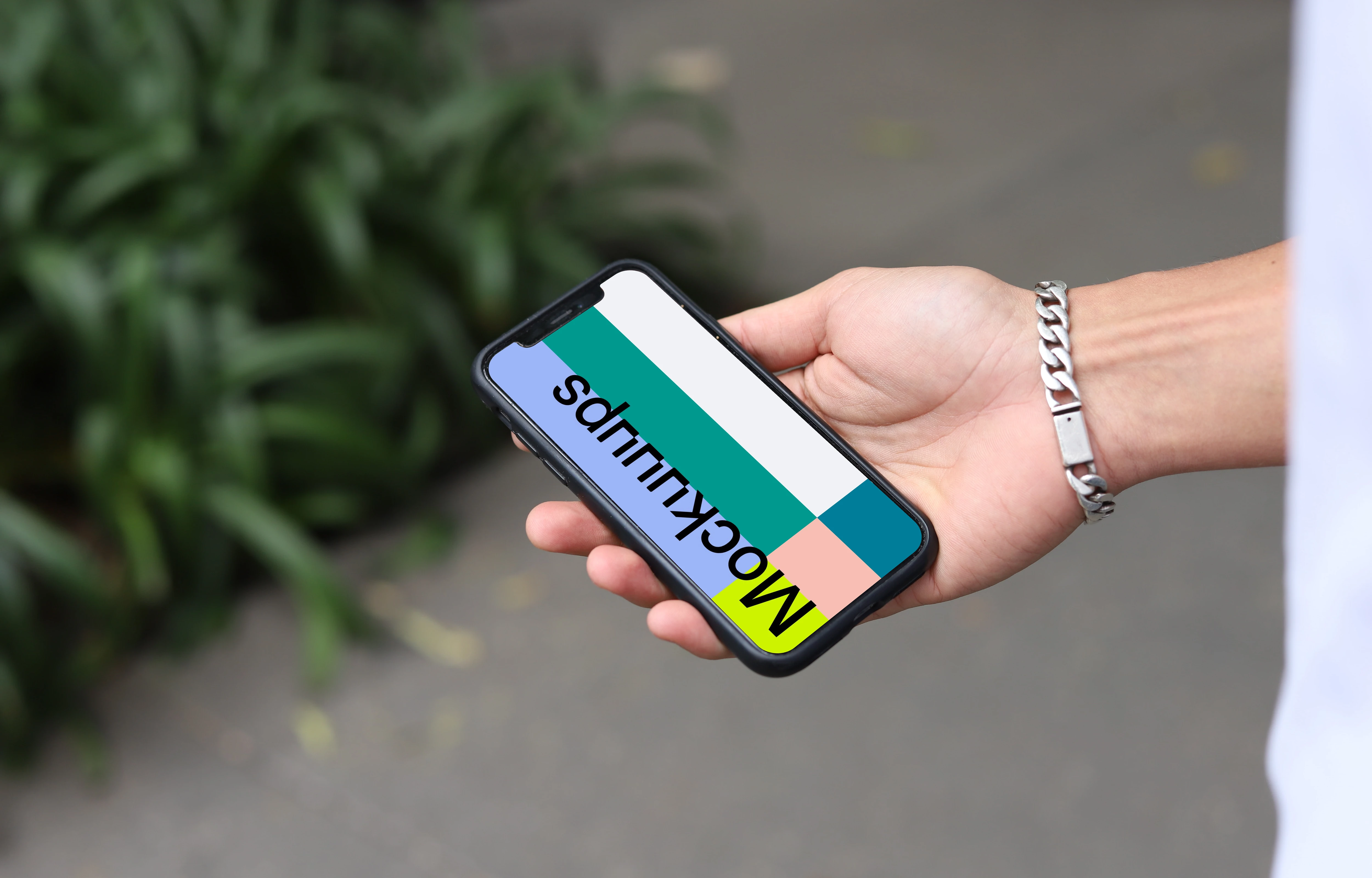 Hand with a bracelet holding an iPhone mockup