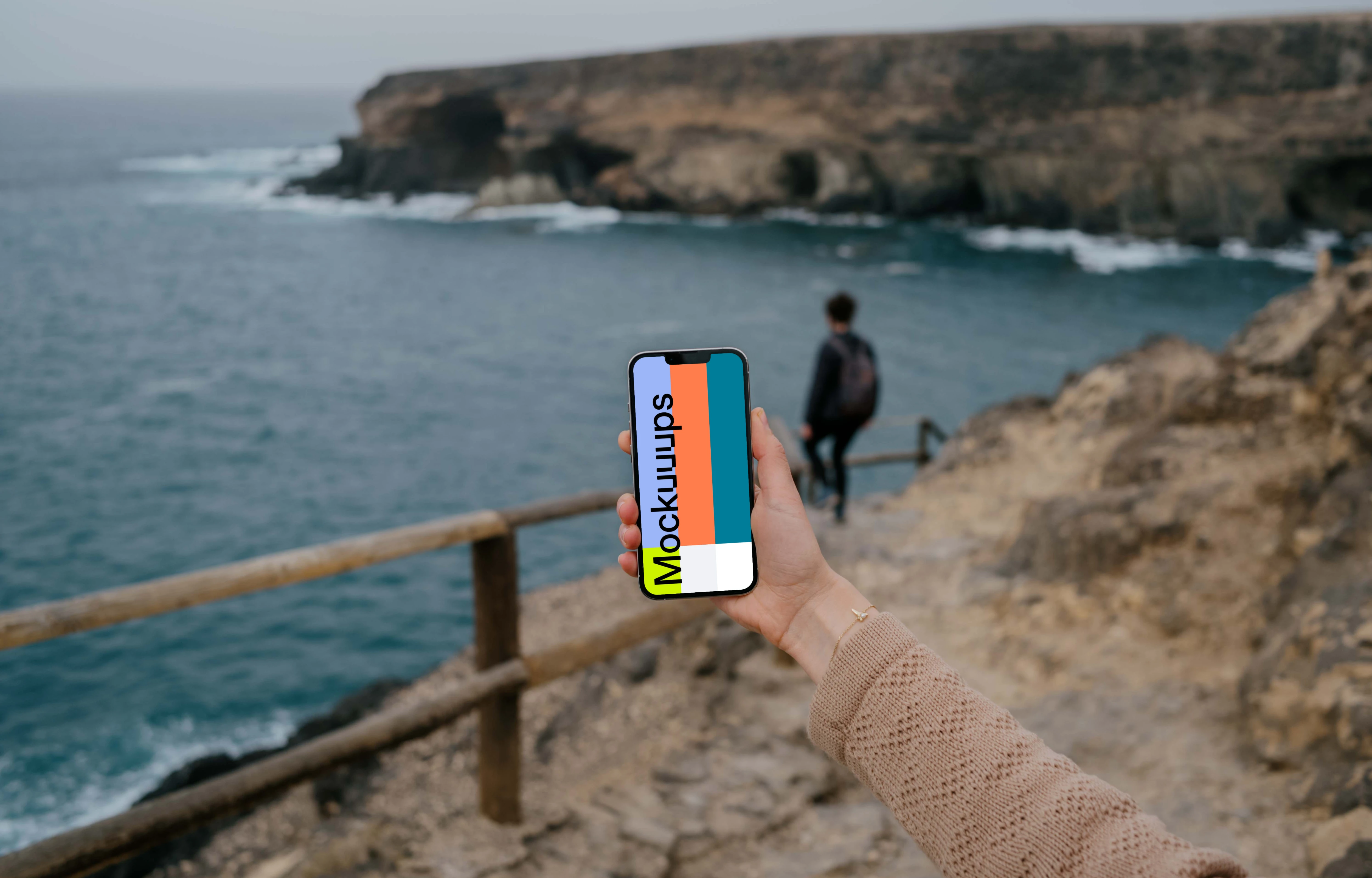 iPhone 13 Pro mockup held by a user at a coastline