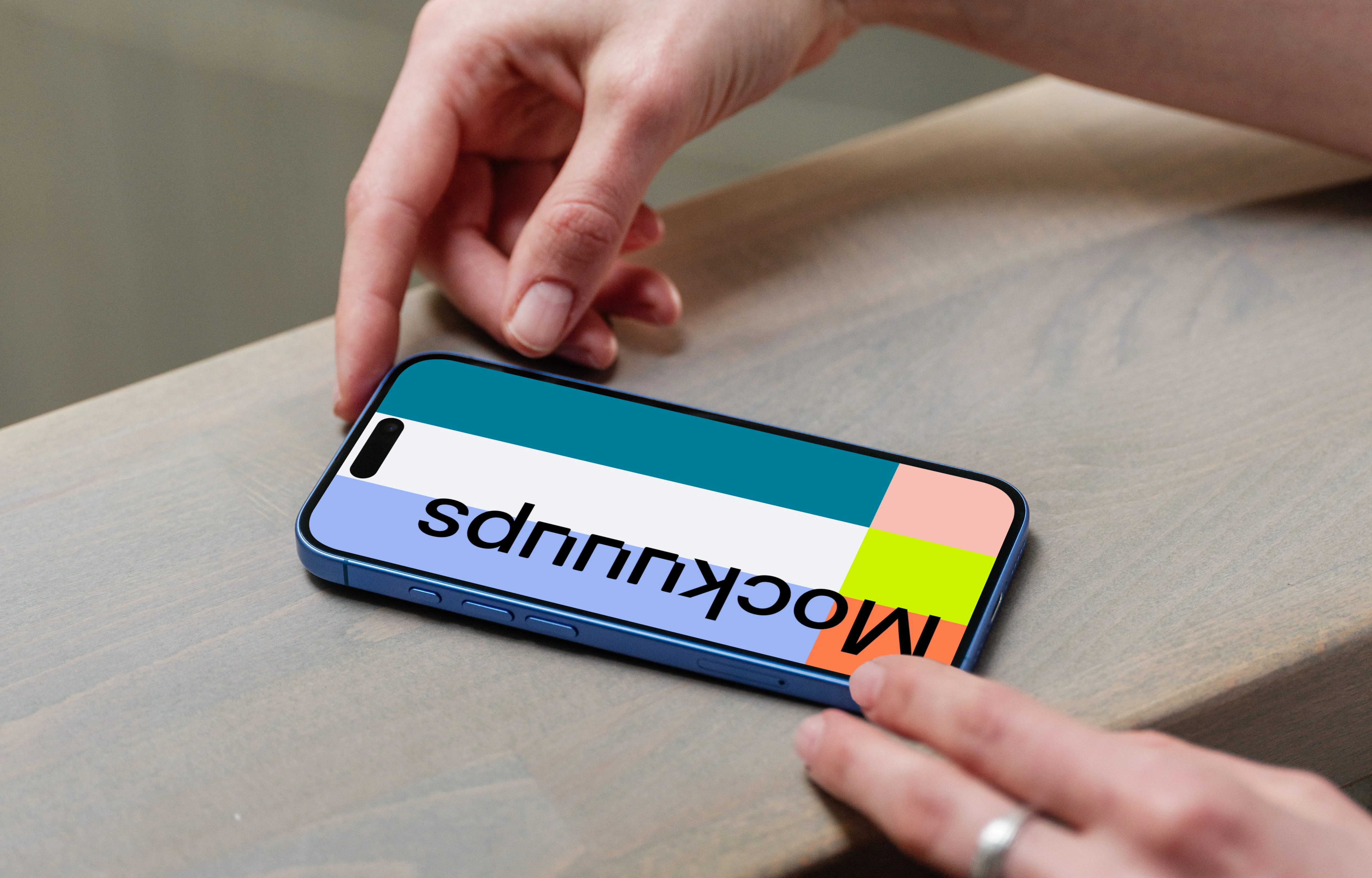 iPhone 16 mockup on a wooden surface with a hand interacting