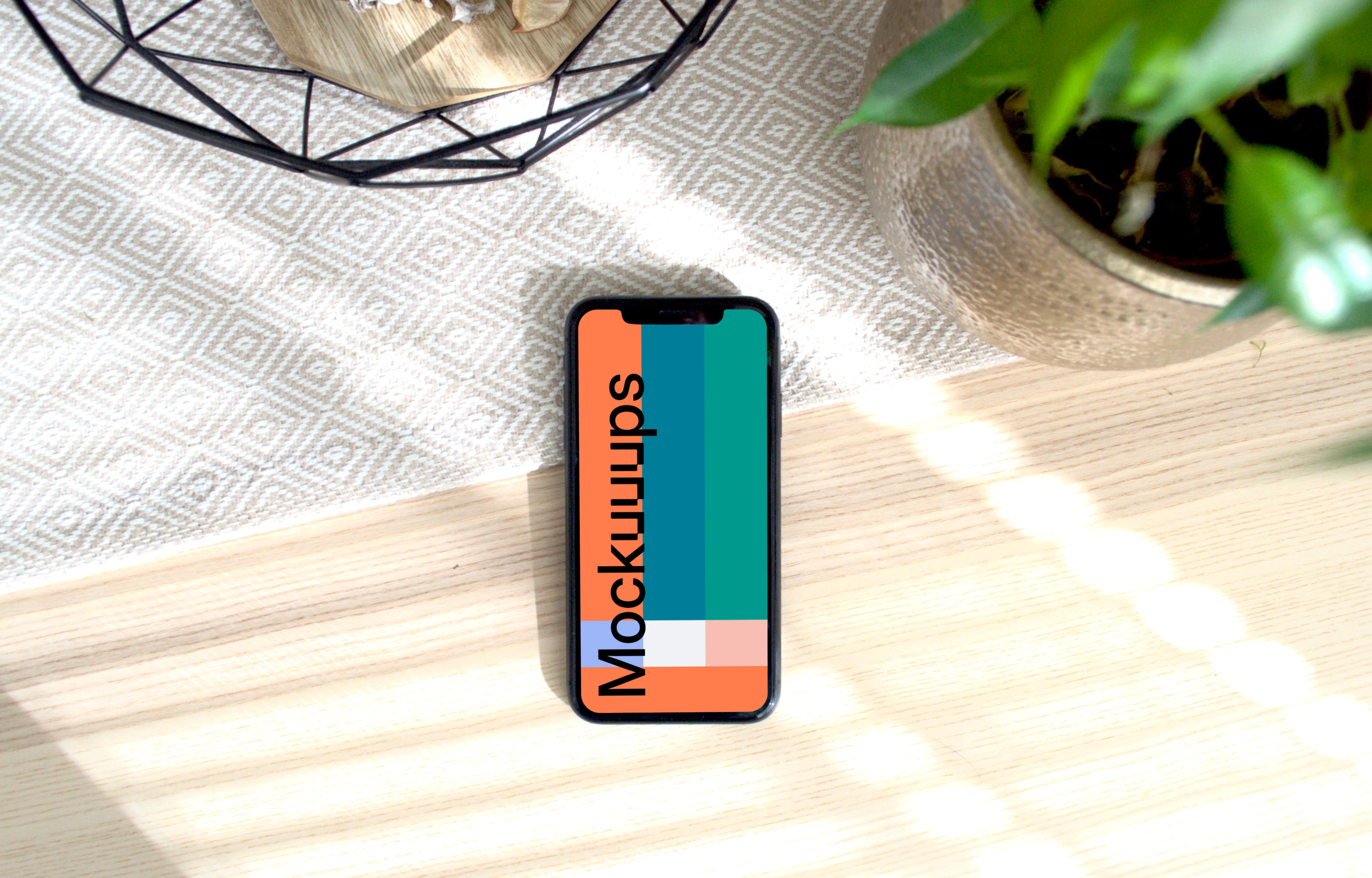 iPhone mockup on a table with a flower pot at the side.