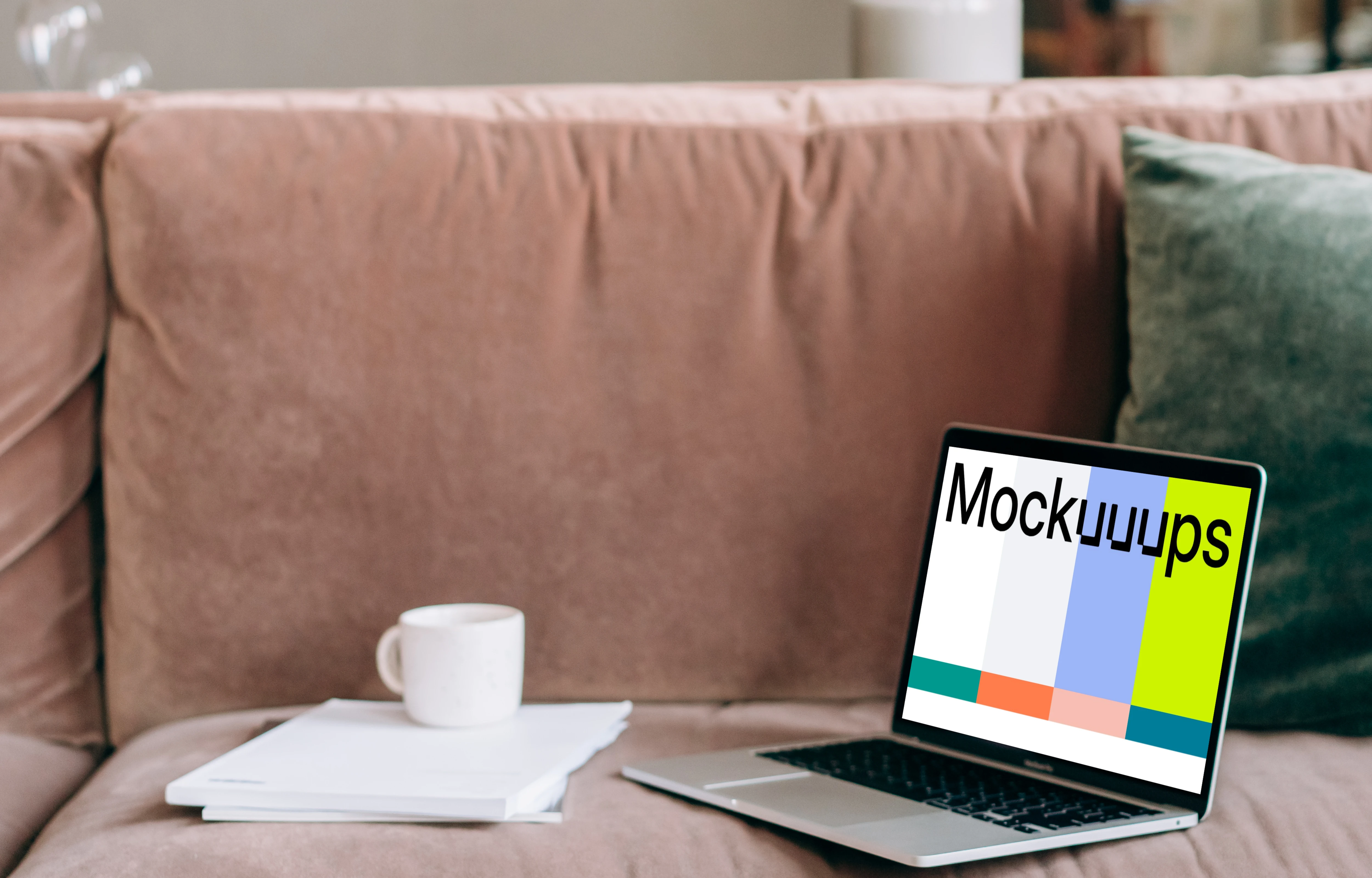 MacBook Pro mockup on a red sofa beside a couple of notepads