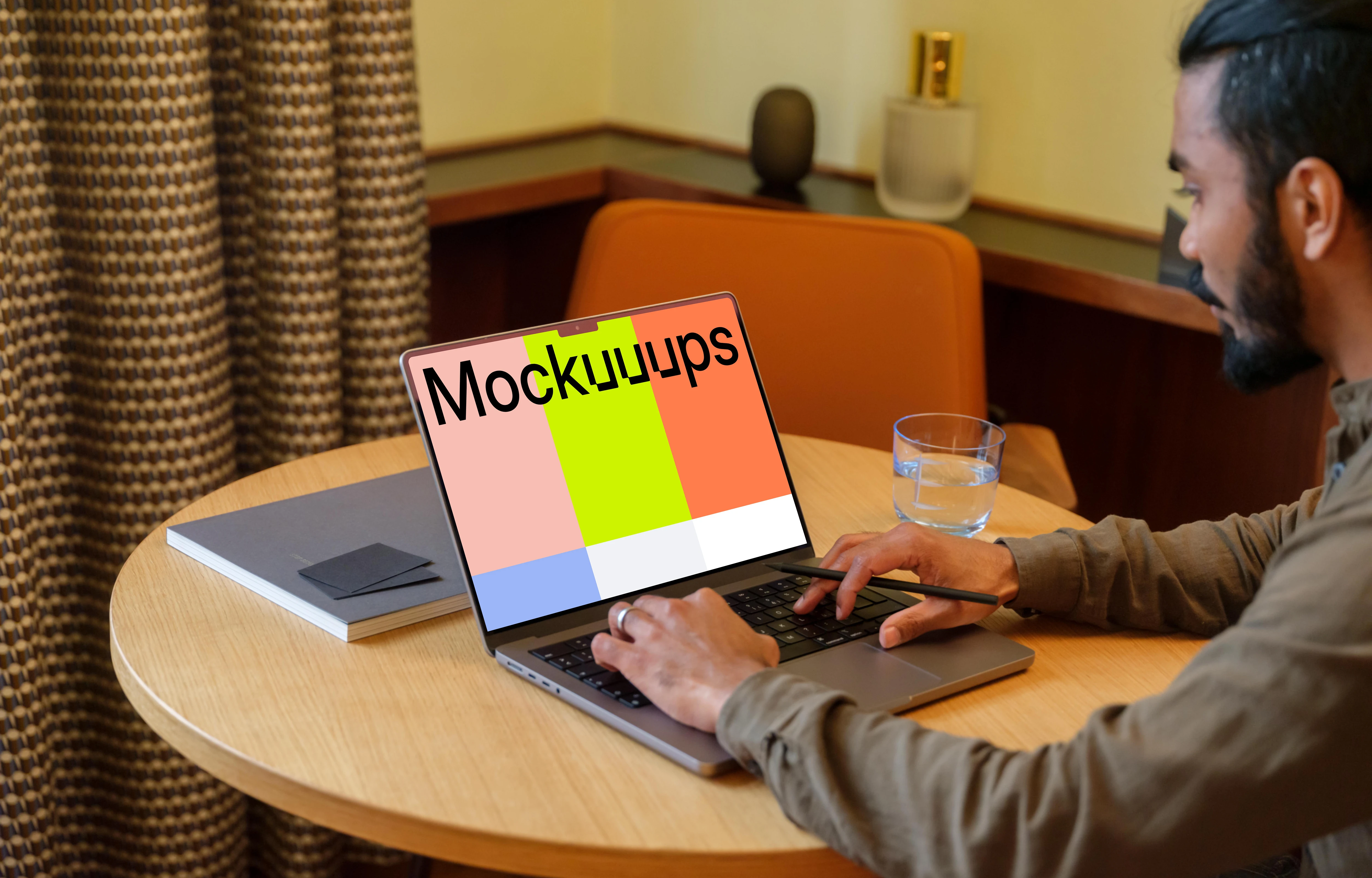 Man typing on a MacBook Pro mockup in a lounge