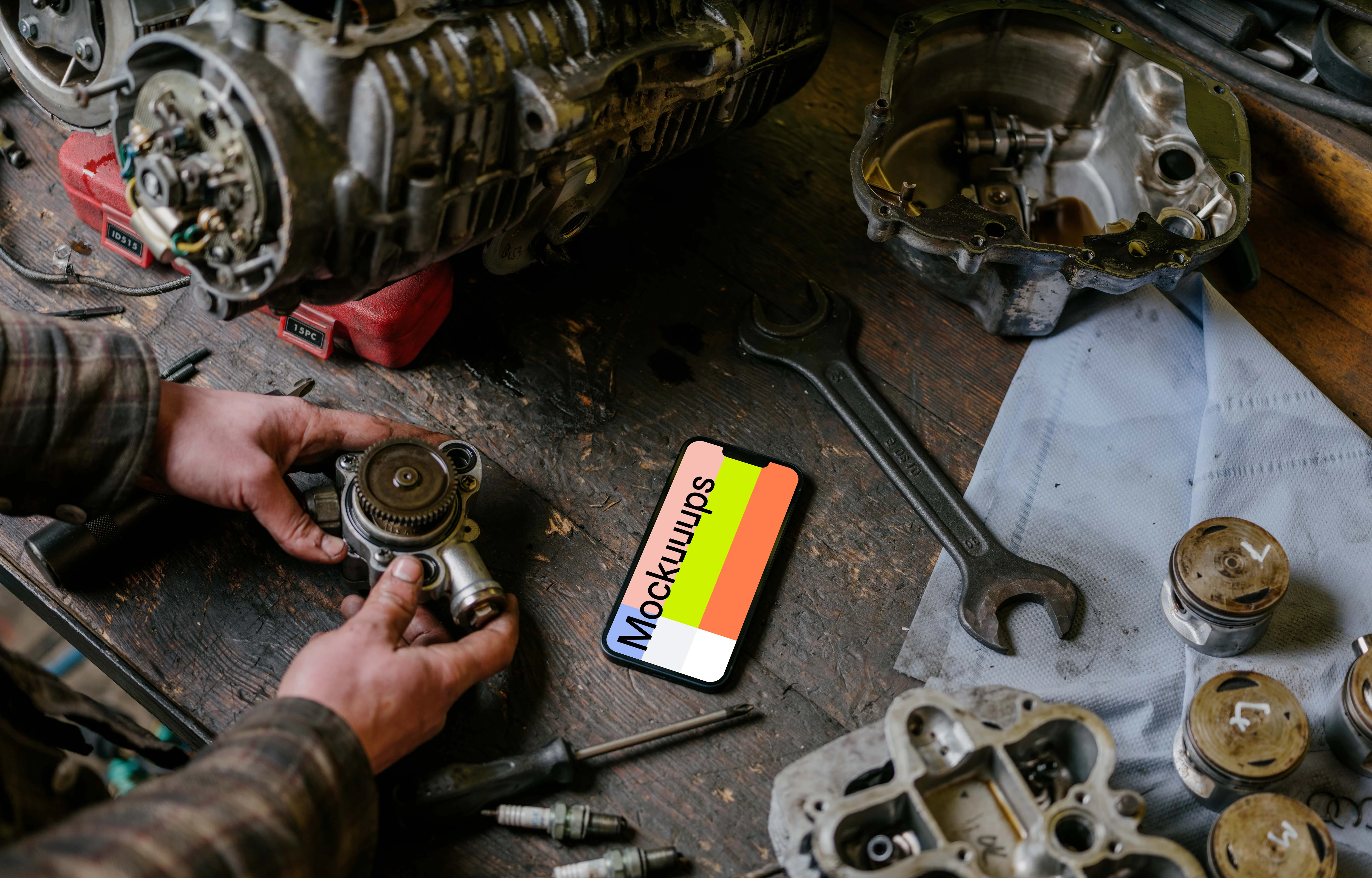 Man with an iPhone 13 Pro mockup on a mechanic worktable
