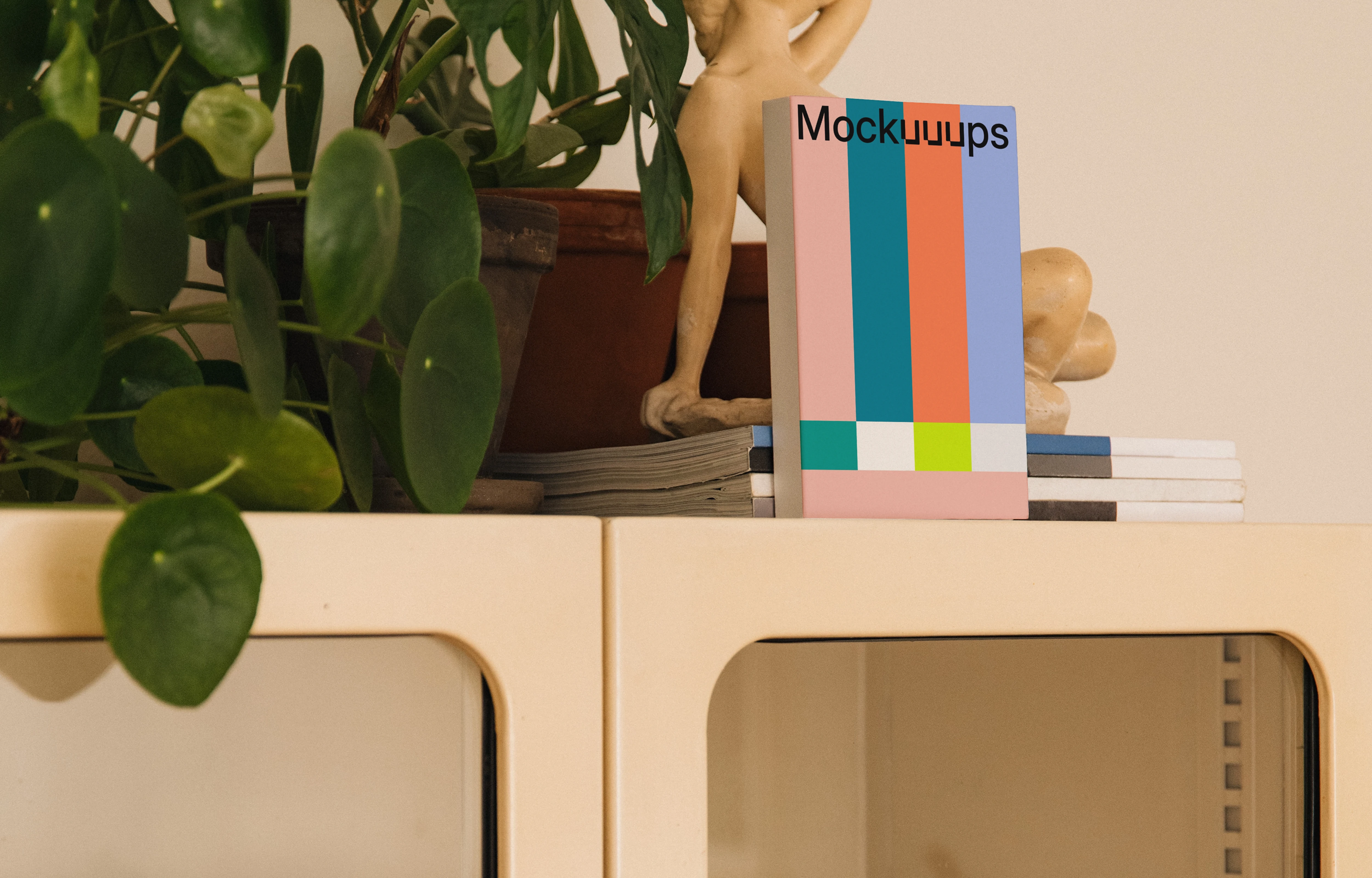 Paperback book mockup on a cabinet with plants