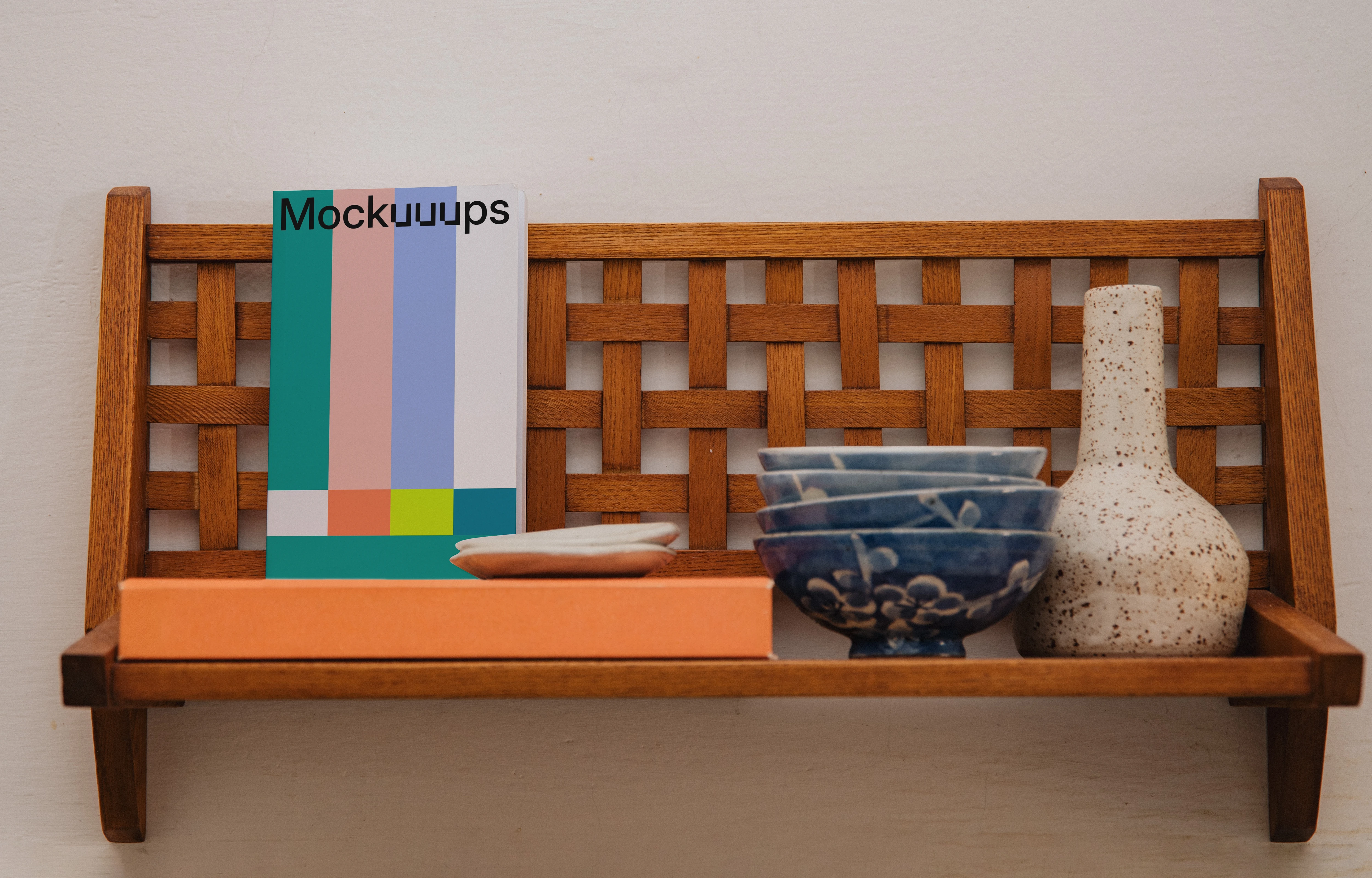 Paperback book mockup on a wooden shelf with ceramic items
