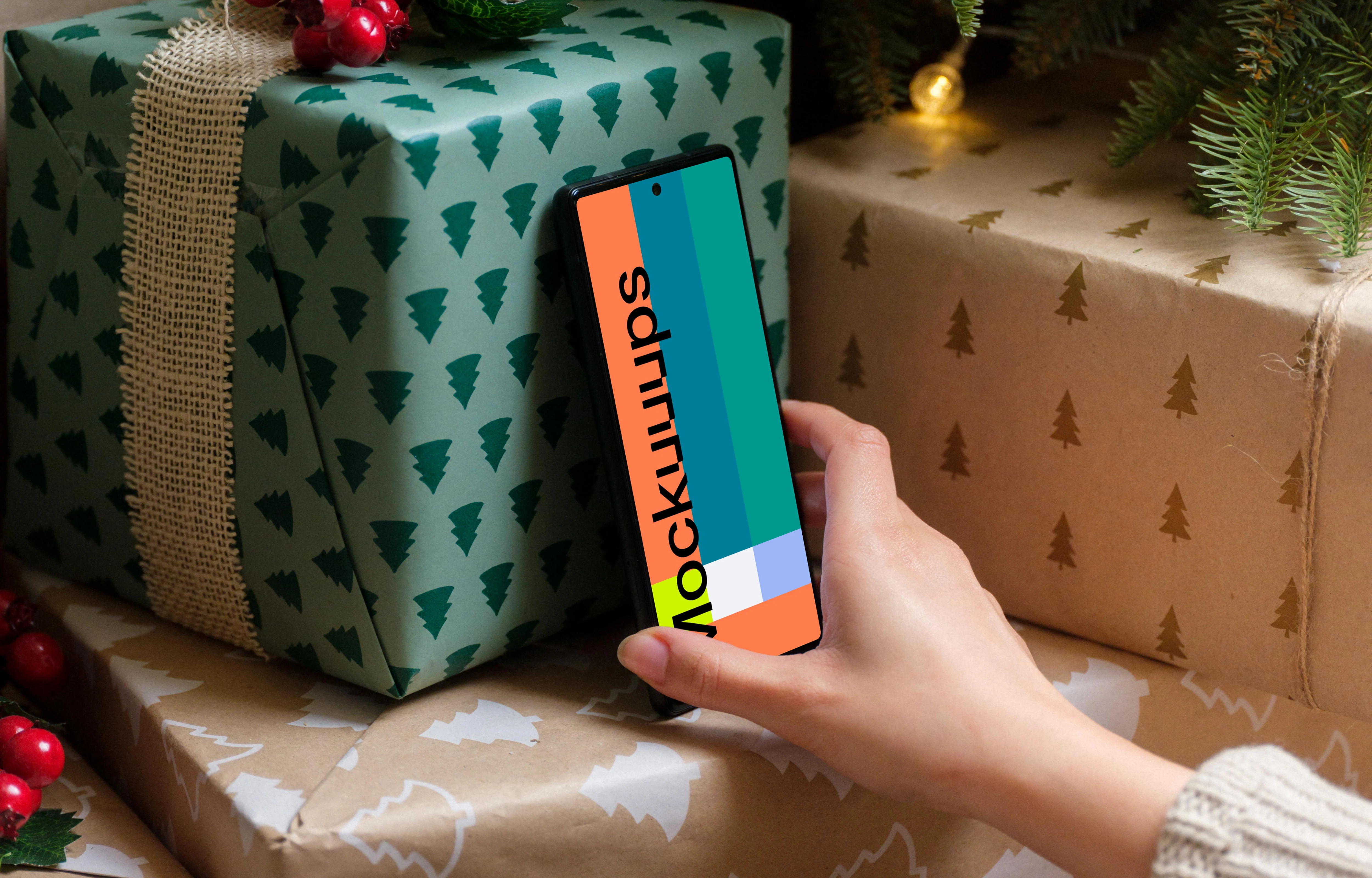 Hand holding a phone mockup under the Christmas tree