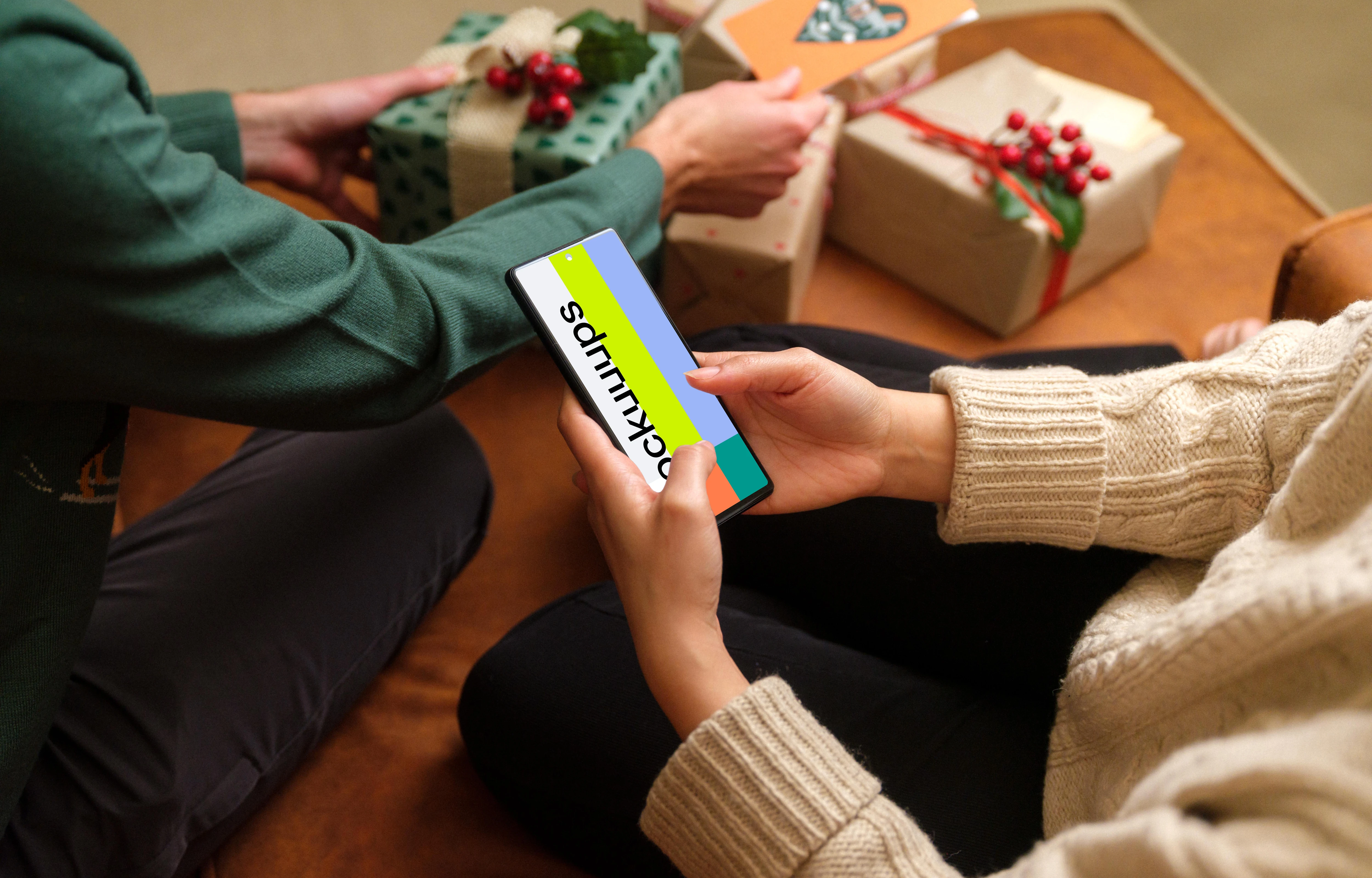 Woman typing on a phone mockup next to the Christmas gifts