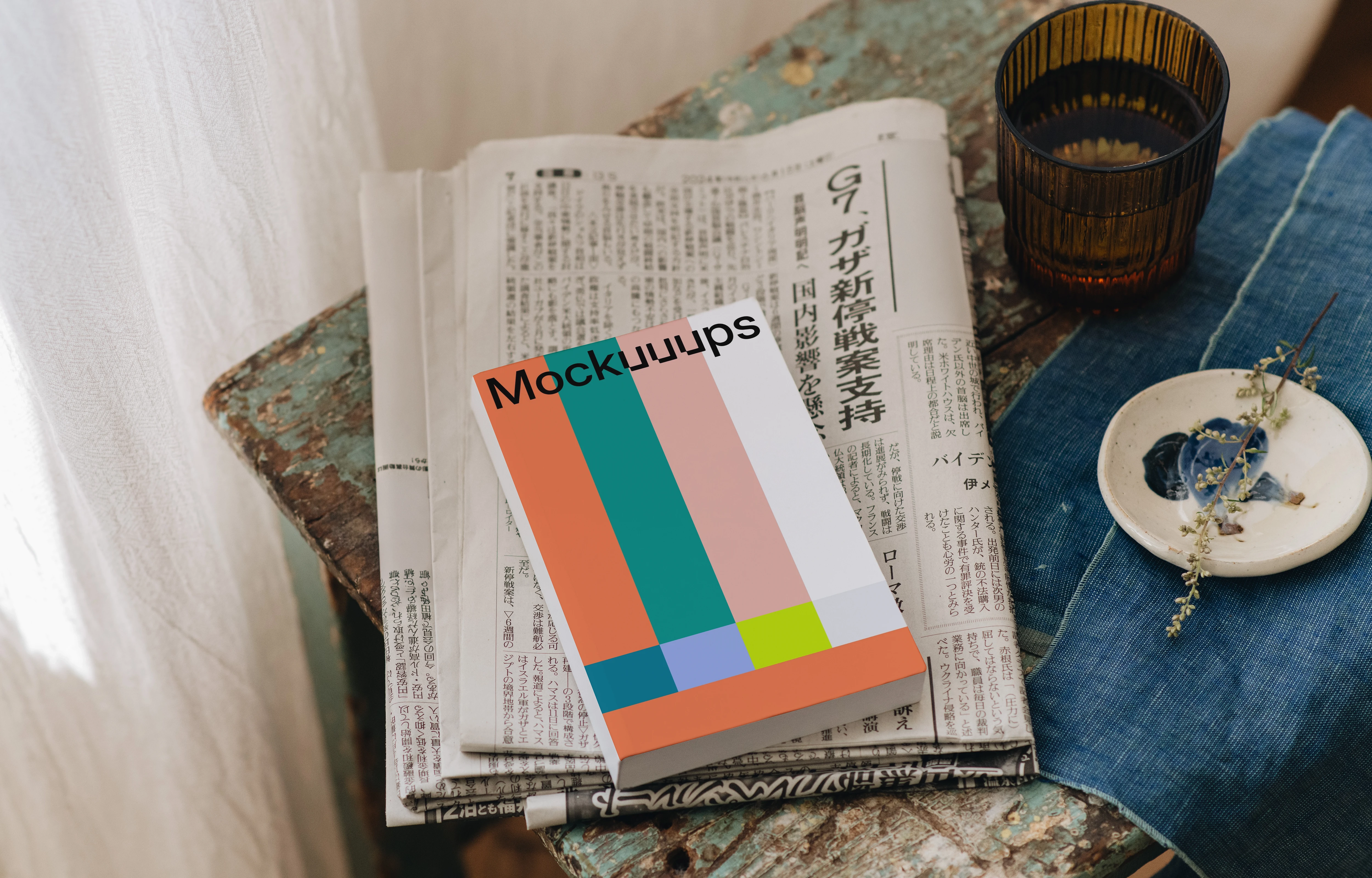 Softcover book mockup on a rustic surface with a cozy setting