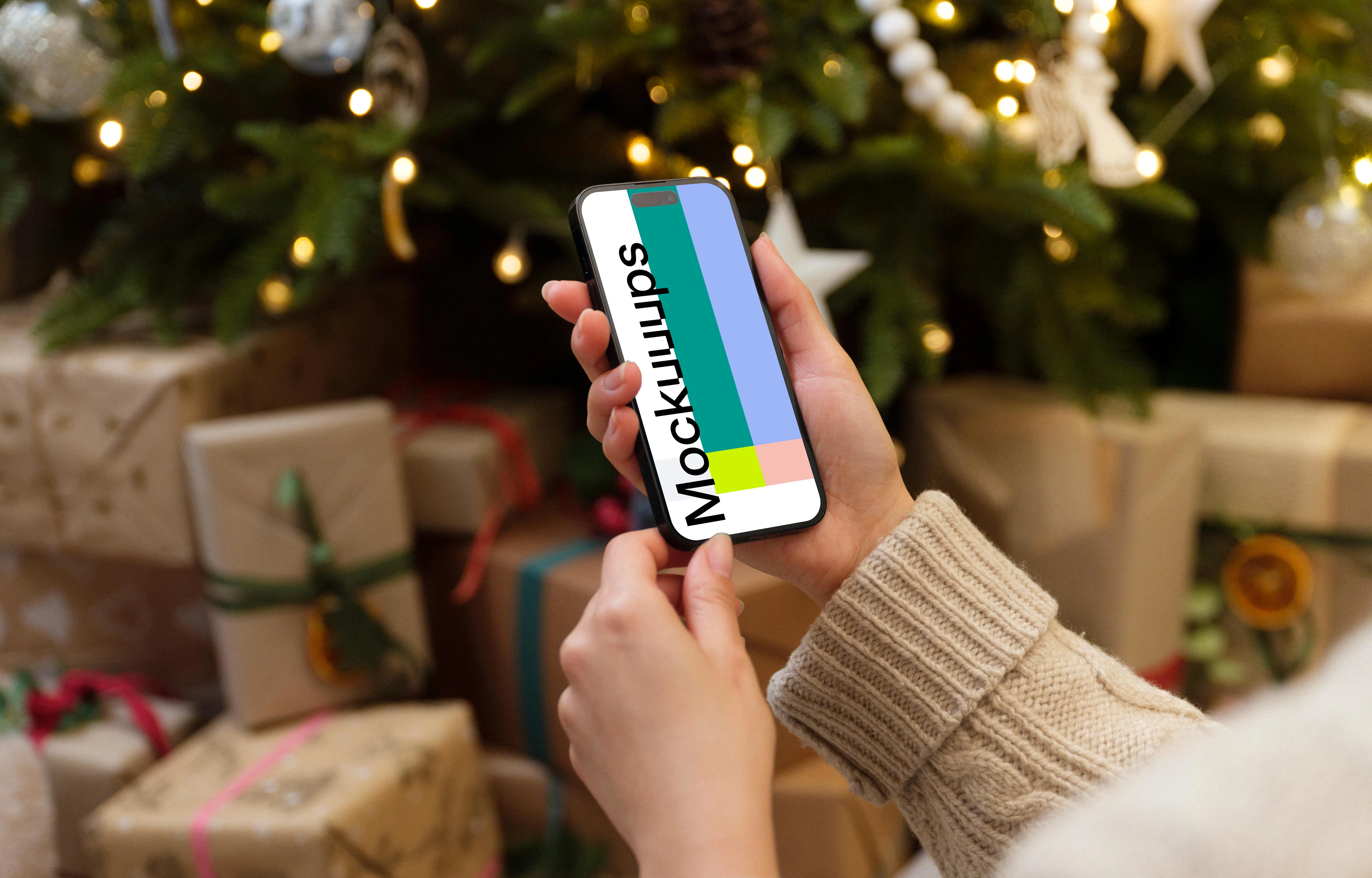 Hand holding a phone mockup next to the Christmas tree with gifts