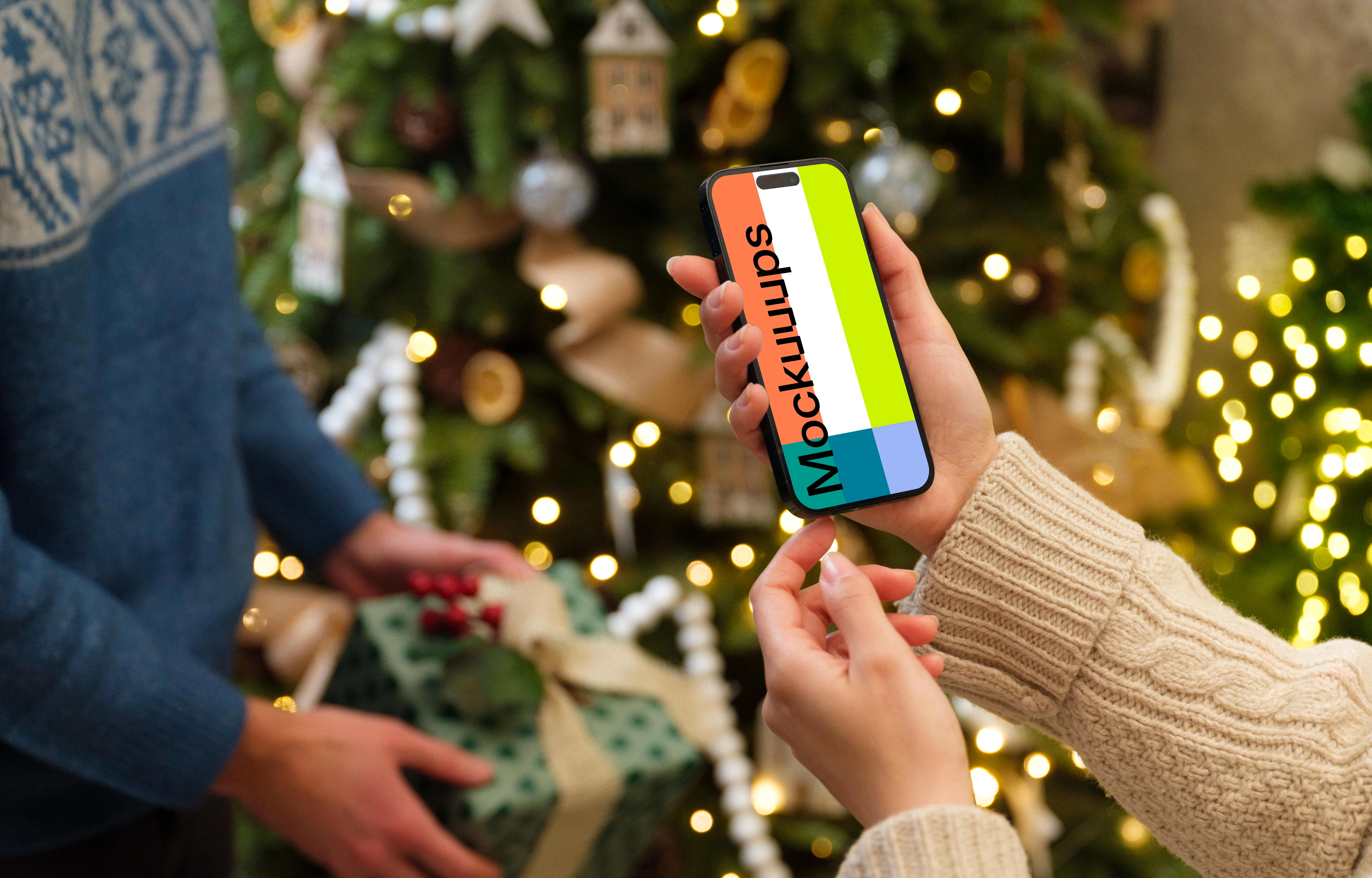 Woman holding an iPhone mockup next to the Christmas tree