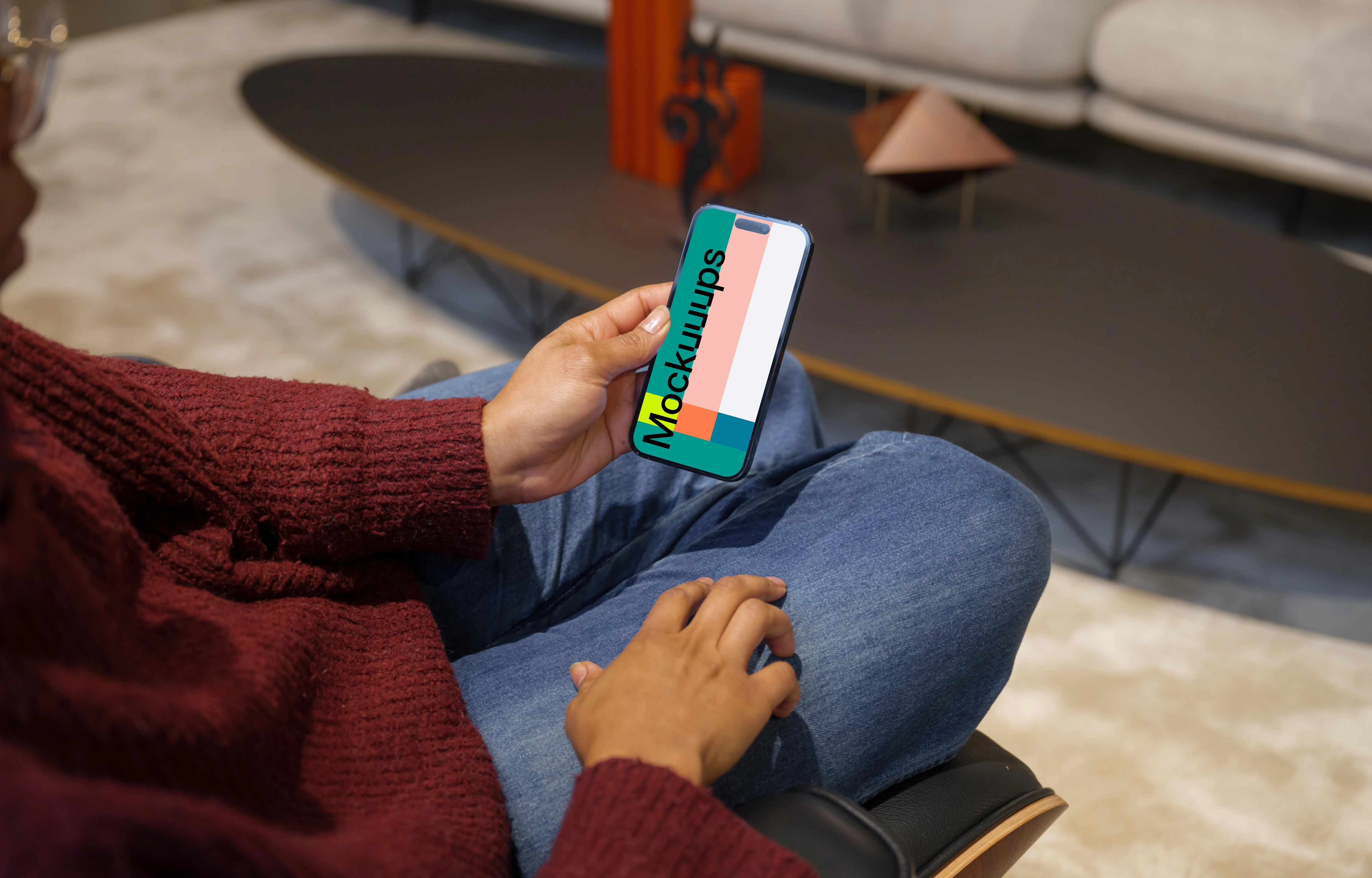 Woman in burgundy sweater holding an iPhone 14 Pro