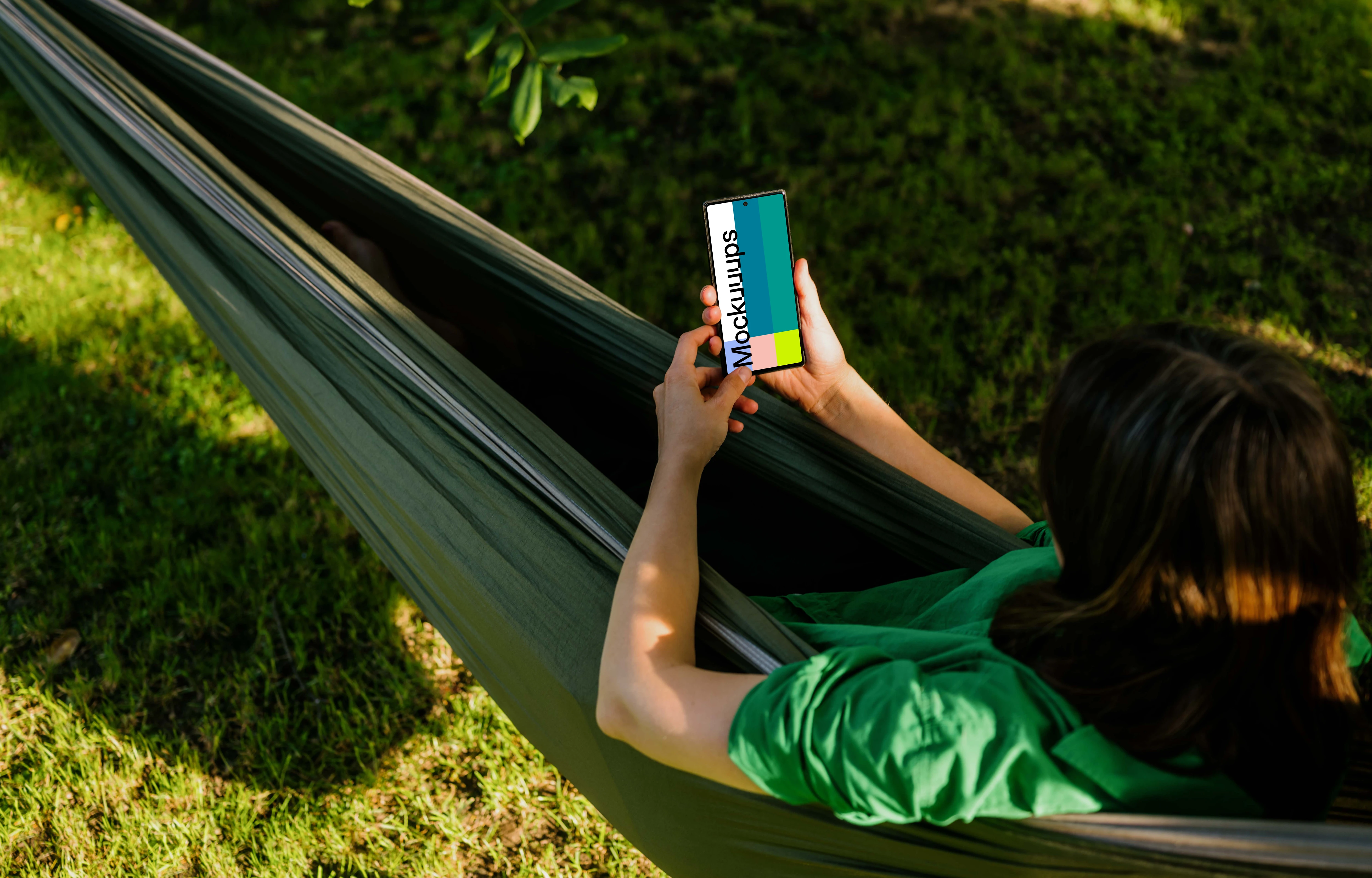 Woman laying in hammock holding a phone mockup