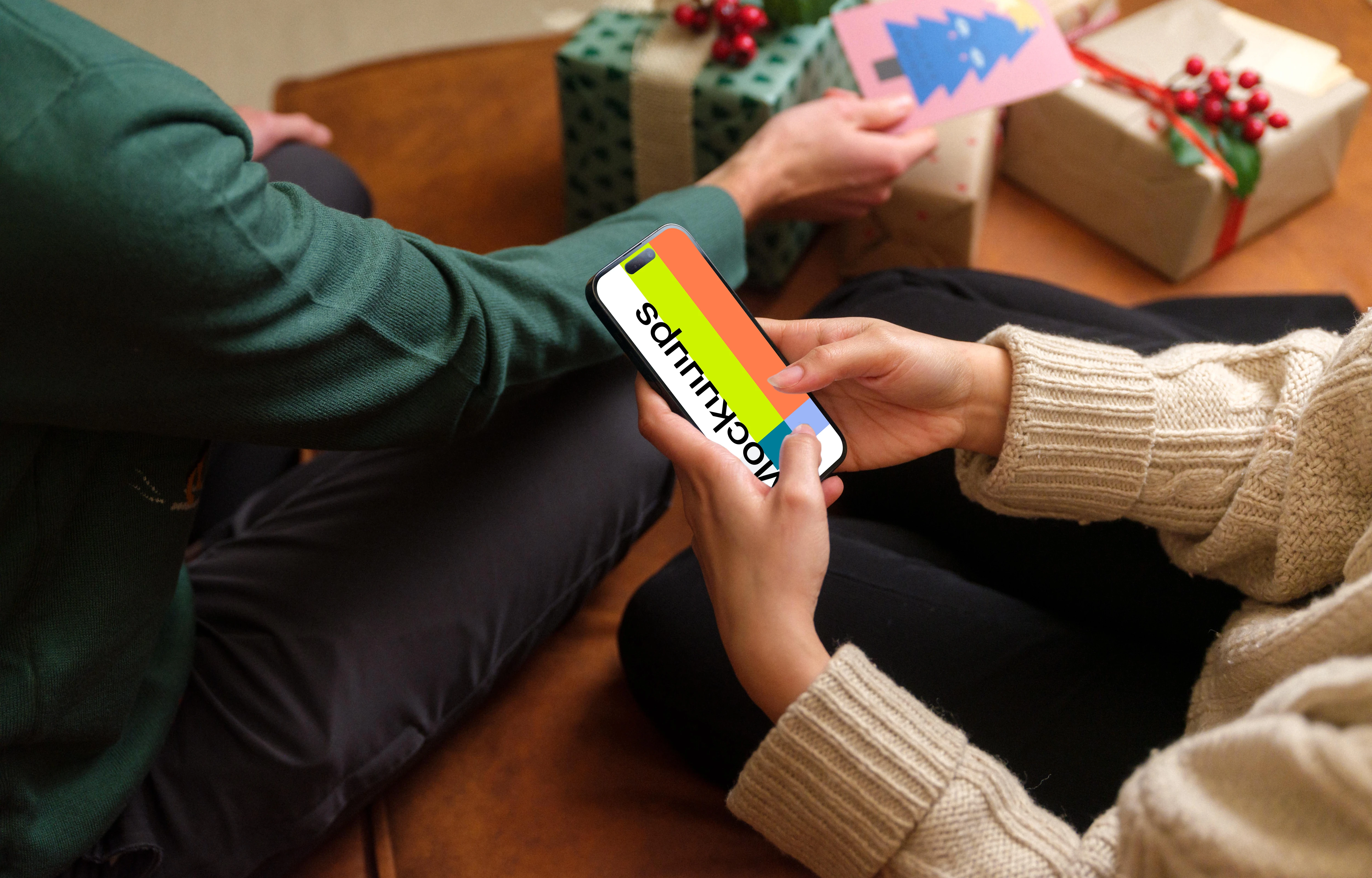 Woman surrounded by Christmas gifts typing on a phone mockup