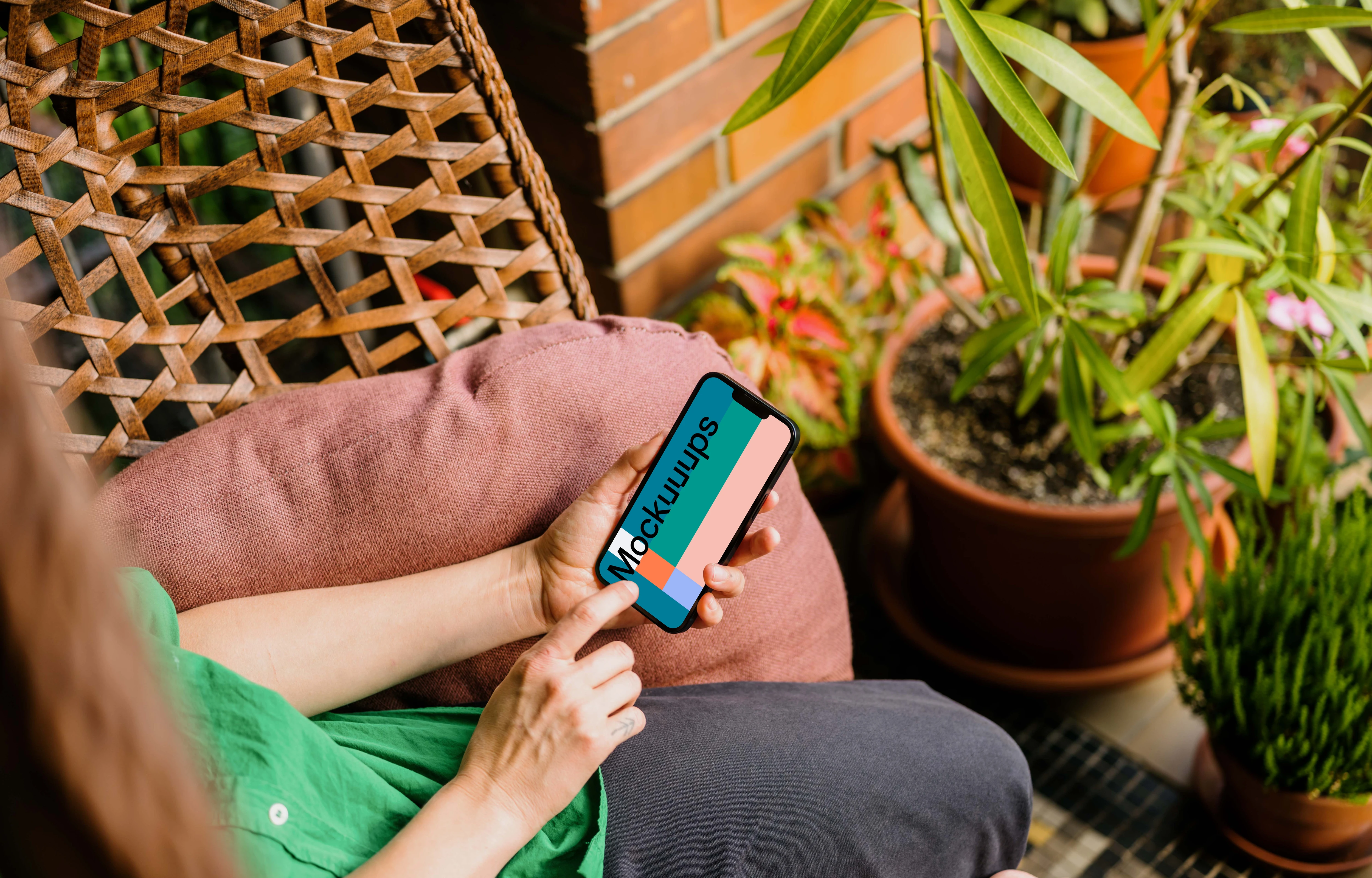 Mujer escribiendo en un iPhone 13 mockup en el jardín