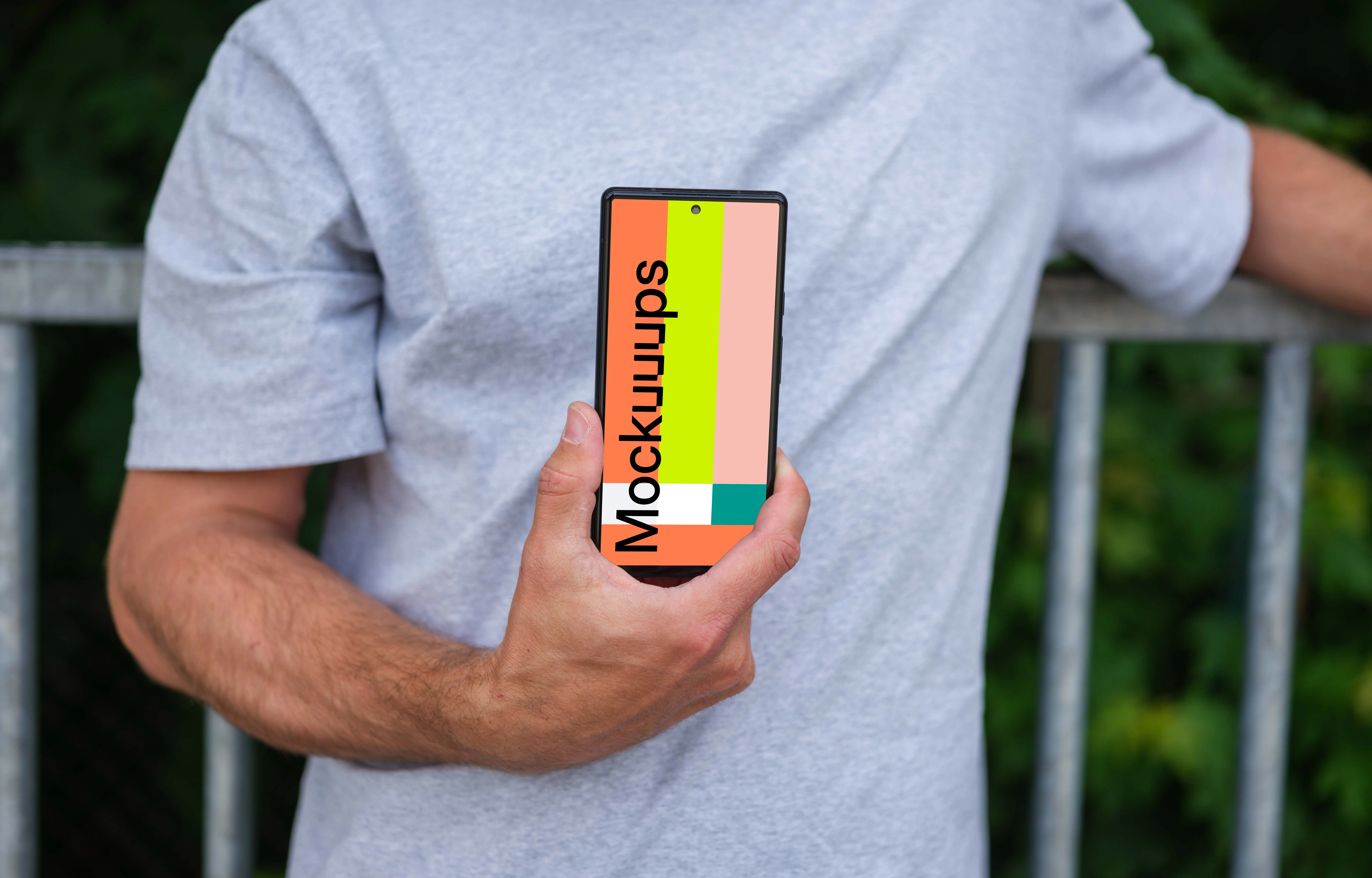 Man holding a phone mockup in front of a fence