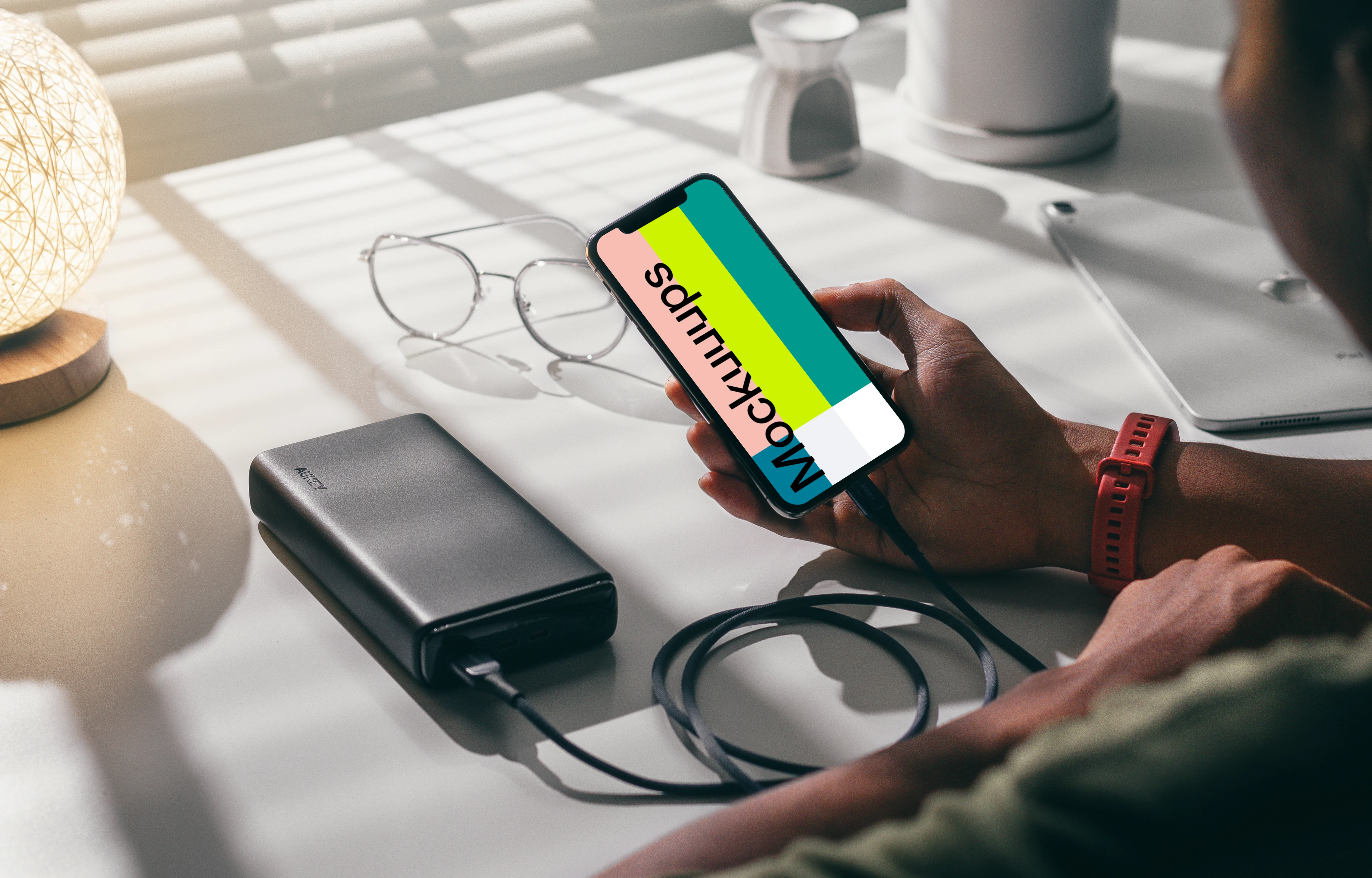 Man holding an iPhone 12 mockup plugged into a power bank