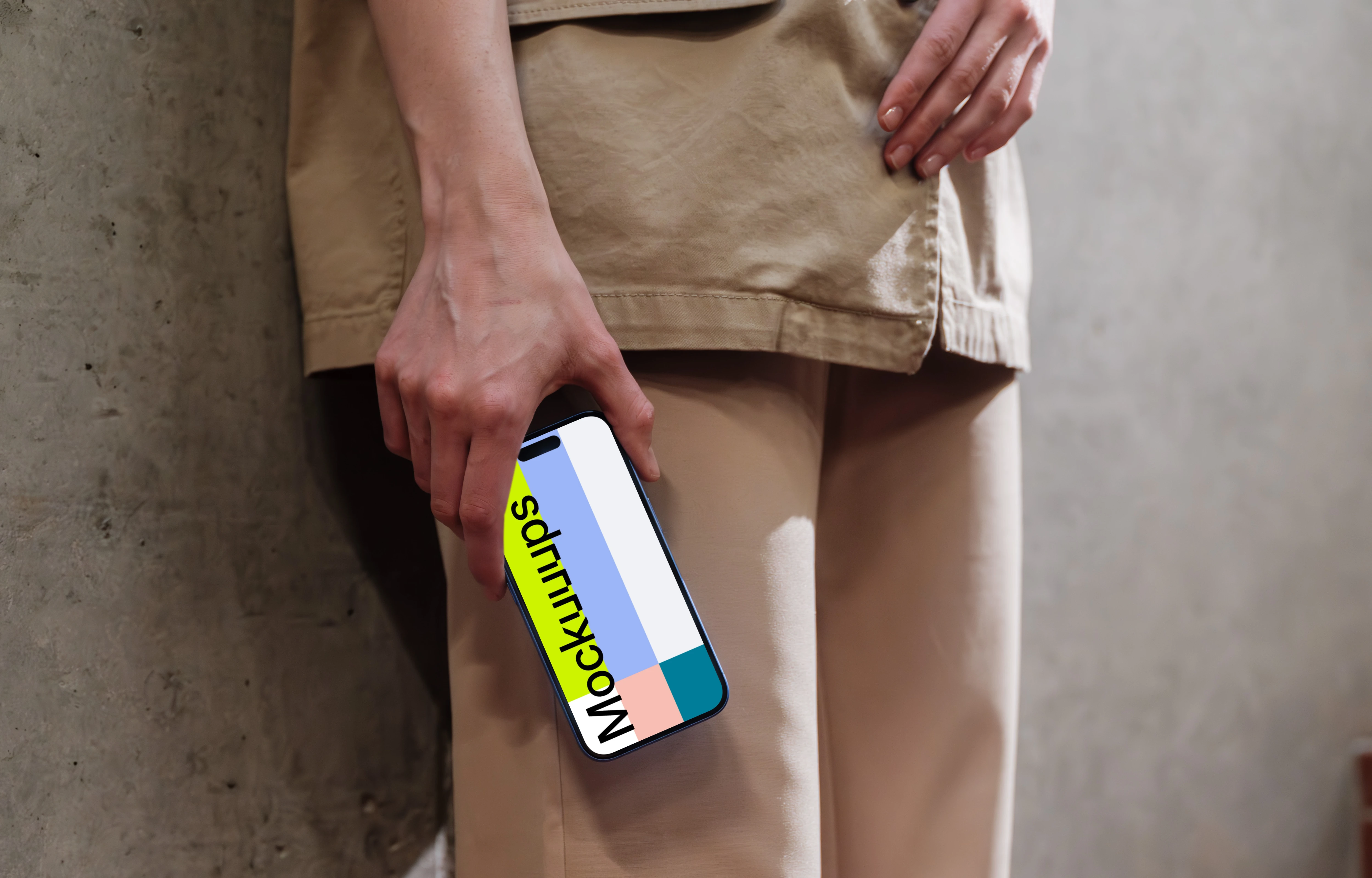 iPhone 16 mockup held by a person against a concrete wall
