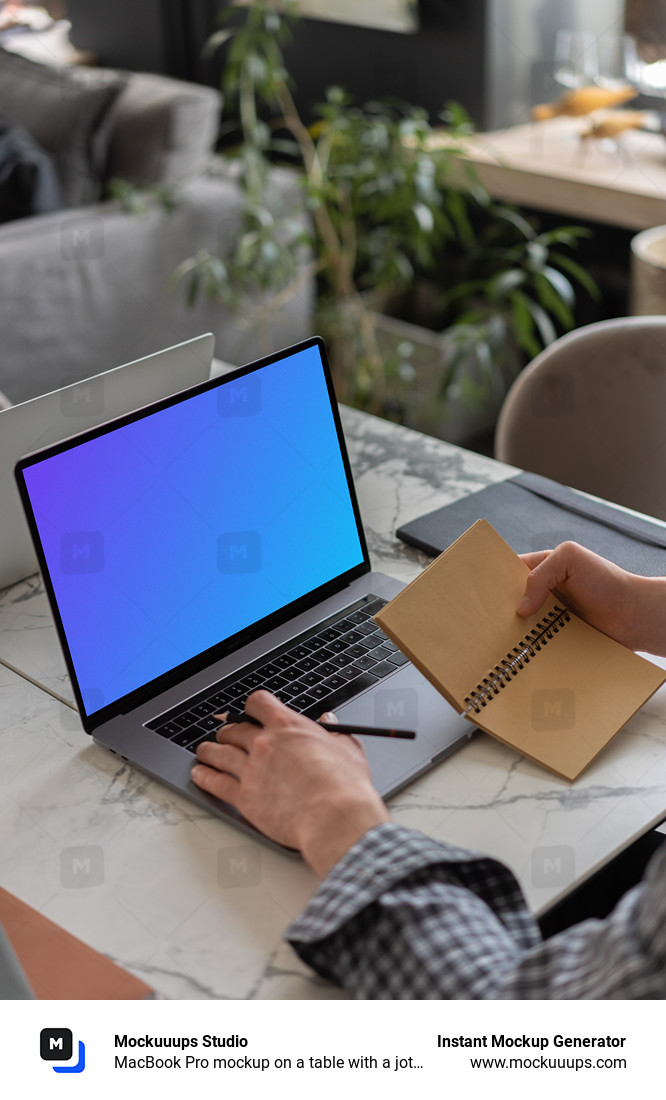 MacBook Pro mockup on a table with a jotter held beside it