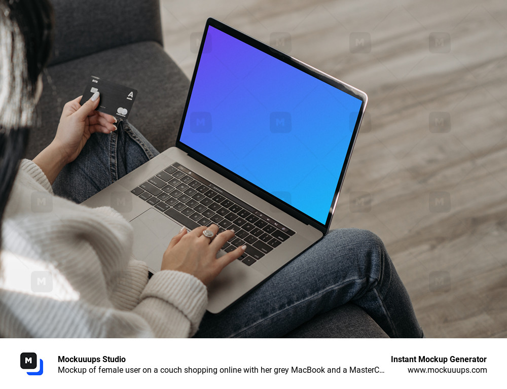 Mockup of female user on a couch shopping online with her grey MacBook and a MasterCard in hand