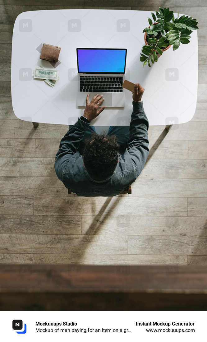 Mockup of man paying for an item on a grey MacBook beside a wallet.