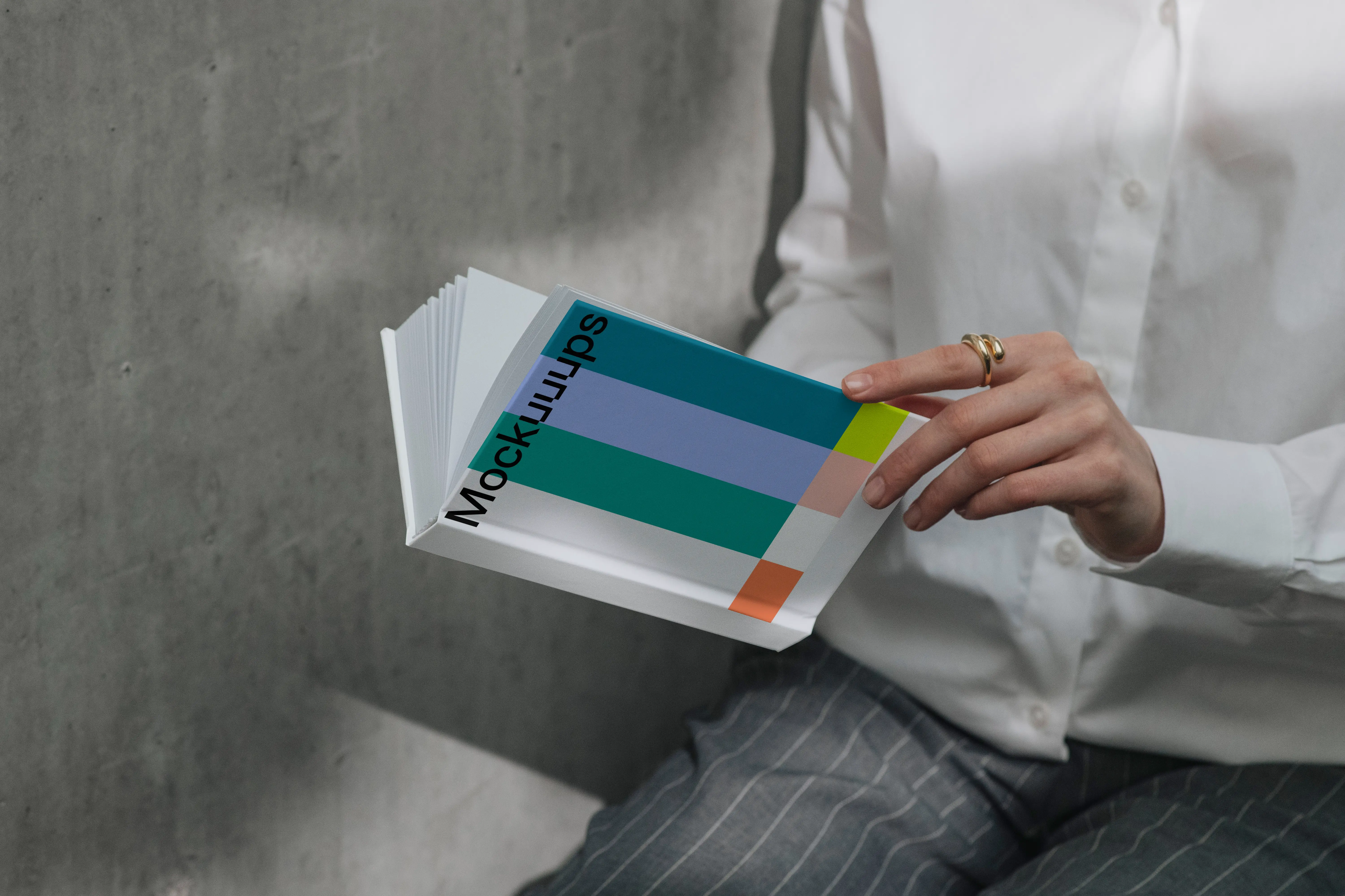 A-format book mockup in hands against concrete wall